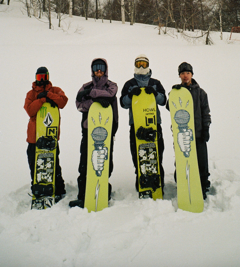 Nitro Alternator Snowboard for 2027 shot with pro riders showing the top sheet and base of this tapered directional snowboard