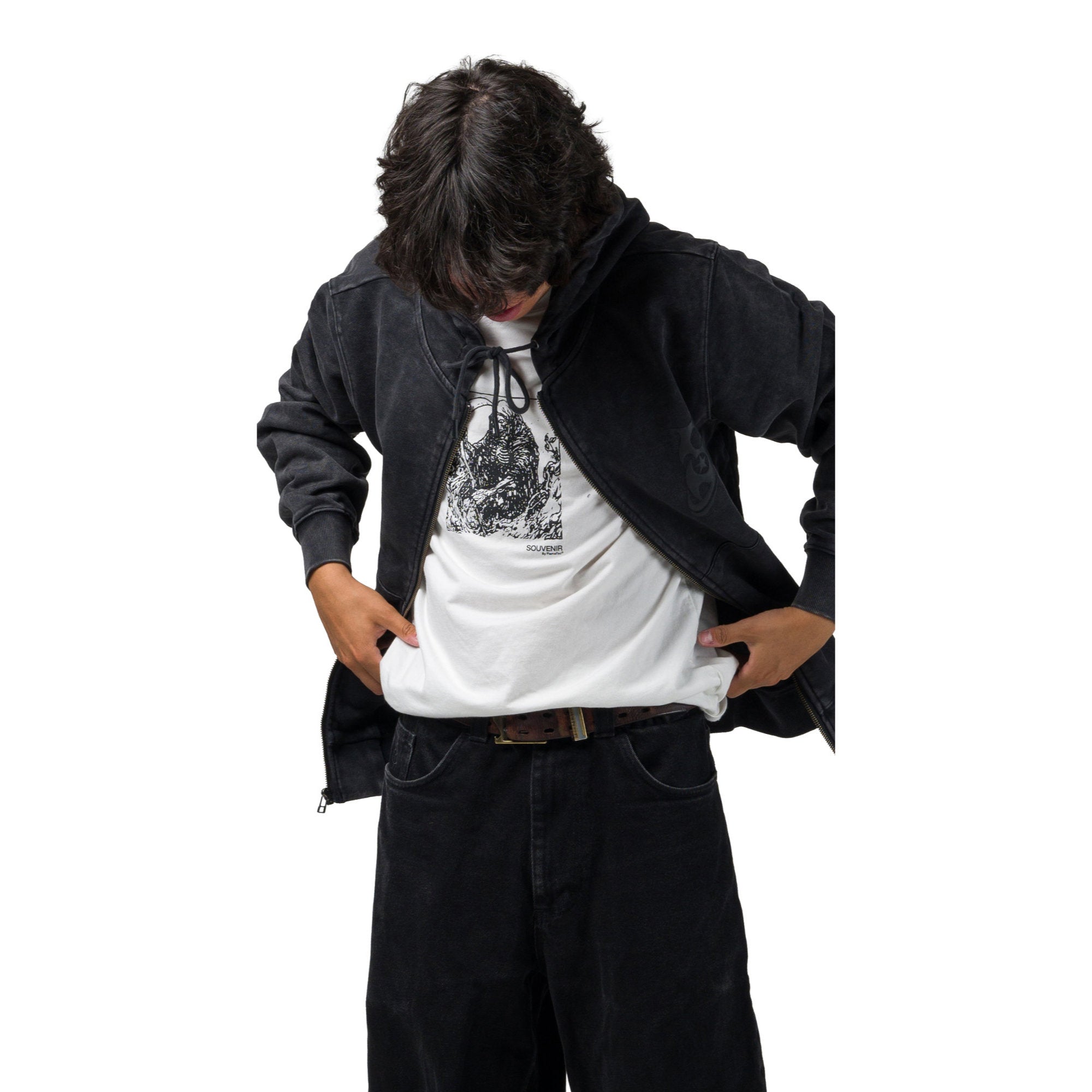 A shredder wearing a black zip up souvenir hoodie over a white graphic t-shirt, paired with dark jeans and a brown belt, standing against a plain white background.