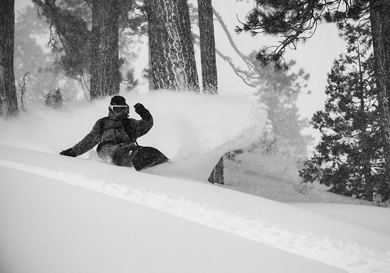 Korua Otto Plus snowboard with a snowy mountain background, showcasing its sleek design and durable construction for winter snowboarding.