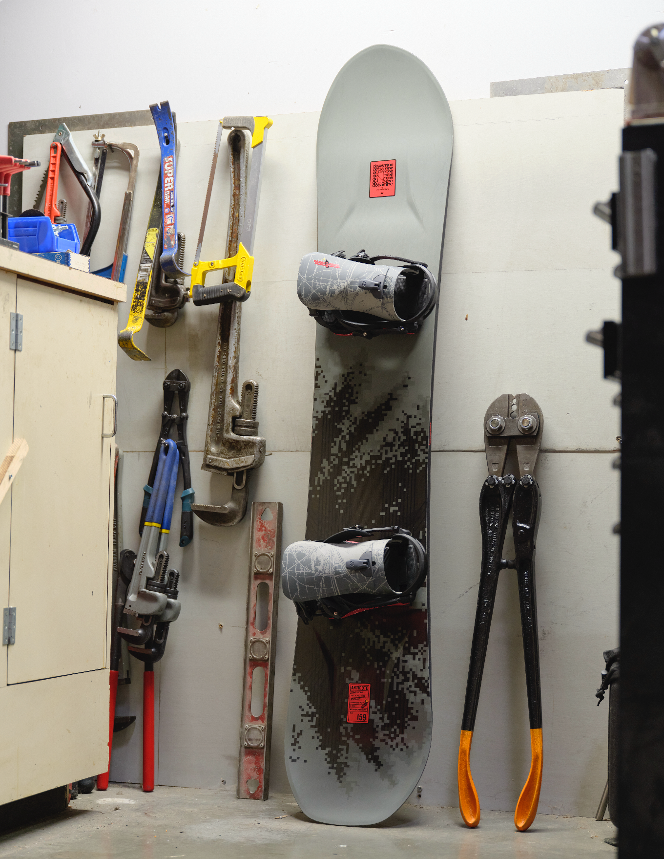 K2 Antidote snowboard 2027 displayed on a workshop wall with bindings and gear, showcasing its design and construction details.