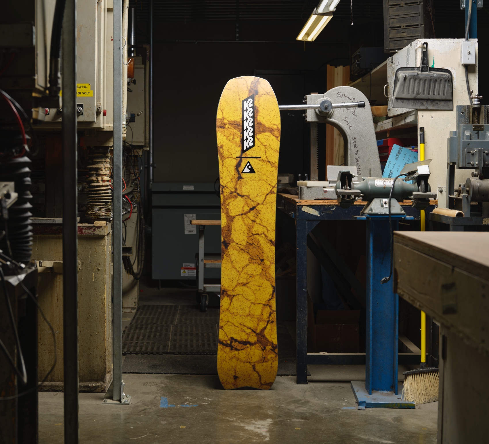 K2 Excavator Snowboard 2027 with detailed base overview showing textured snow surface and snowboard design for winter riding.