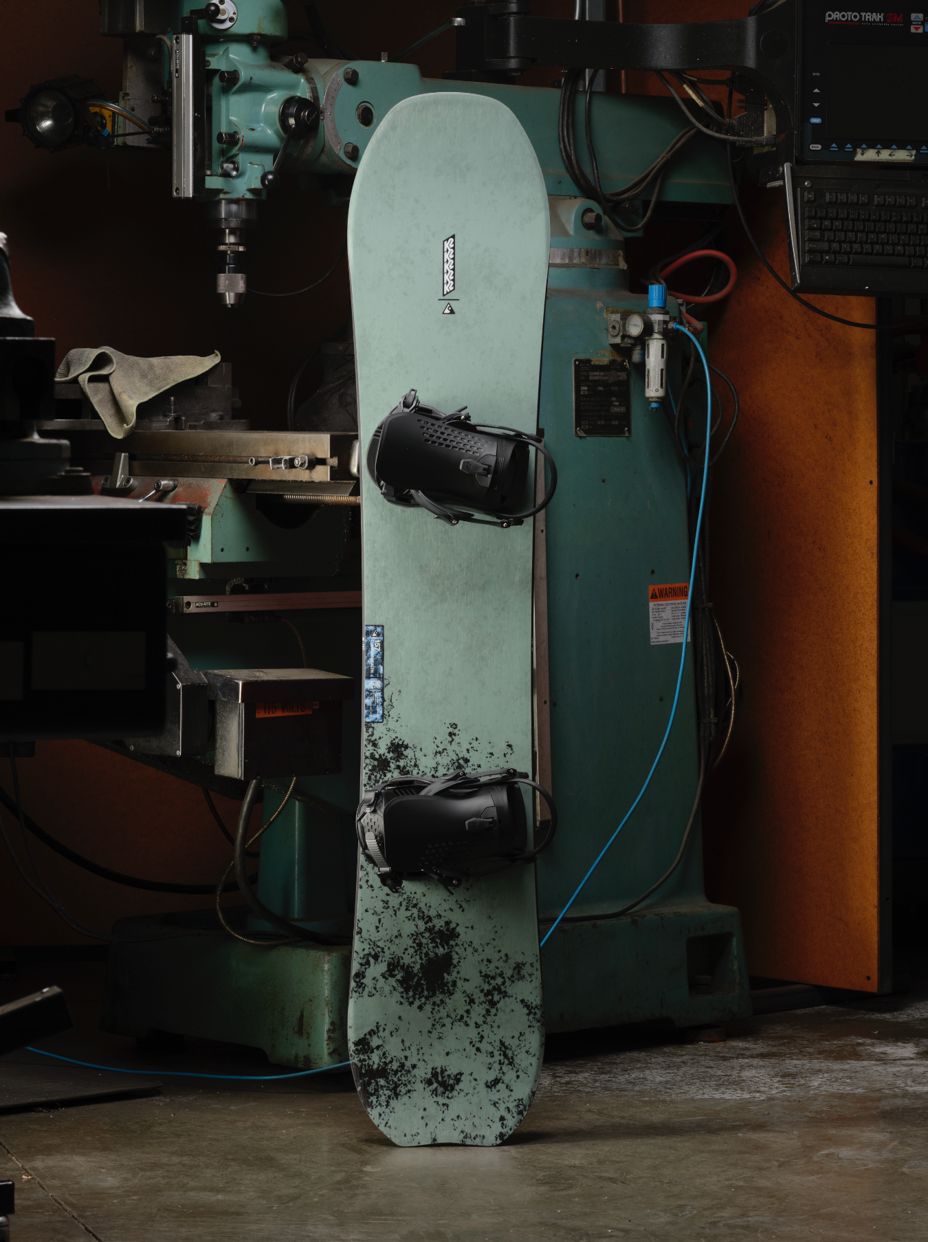 K2 Commonwealth Snowboard 2027 with a sleek design, suitable for snowboarding enthusiasts, shown on a workshop background.