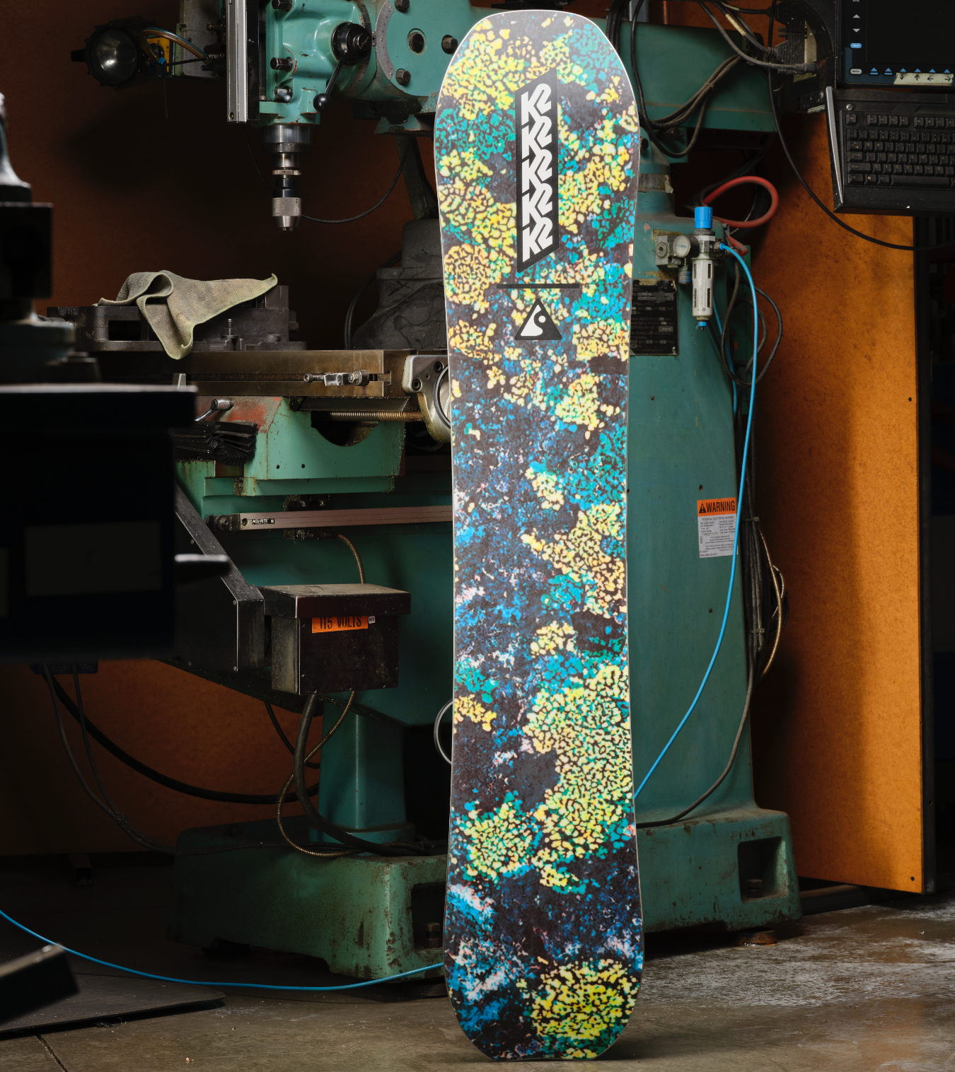 K2 Passport Jr Snowboard 2027 for kids, showing the base with factory finish and colorful graphics on the snow.
