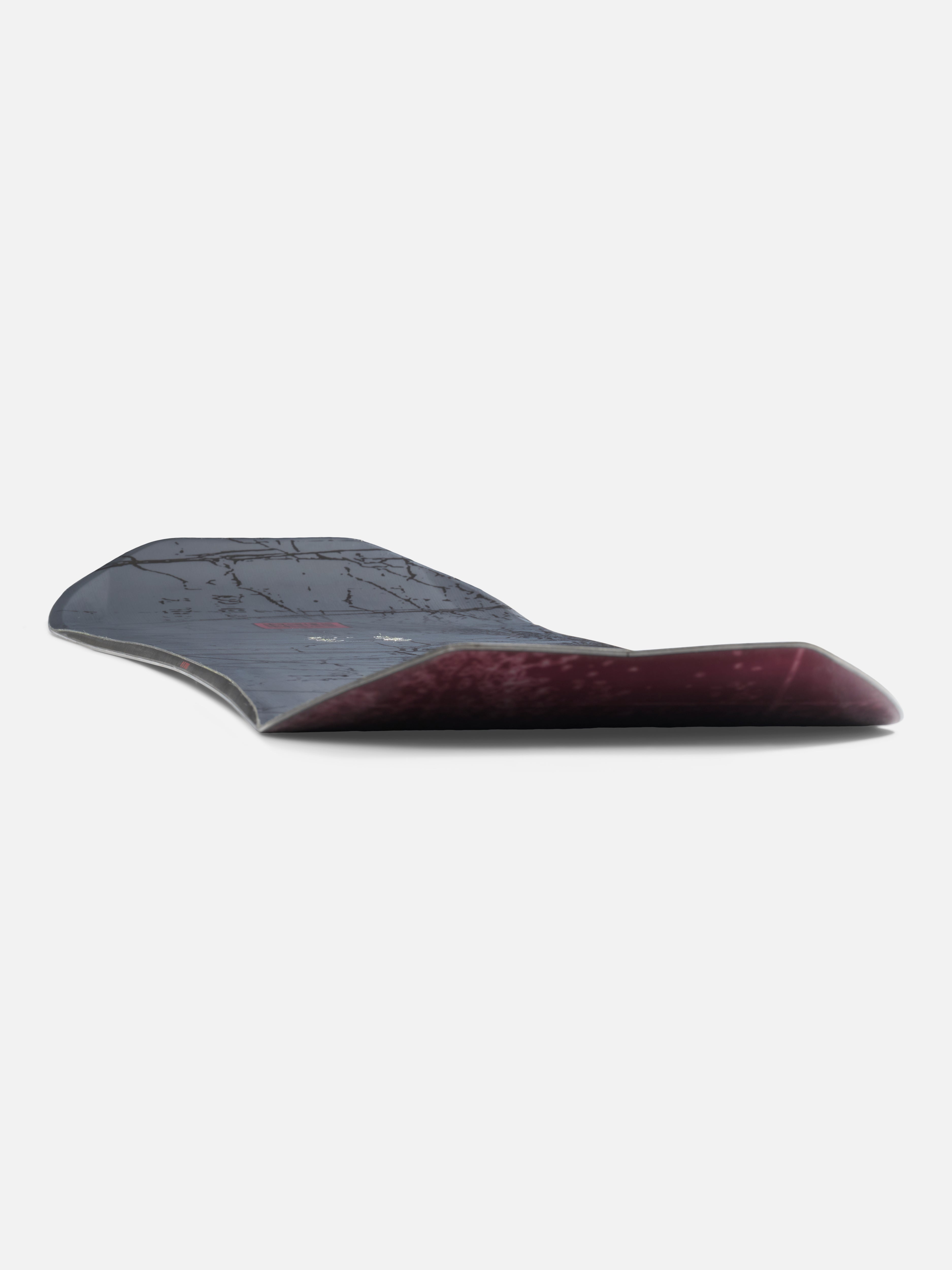K2 Sky Pilot Snowboard 2027, low-angle view showing its sleek black design and snowboard shape with bindings attached.