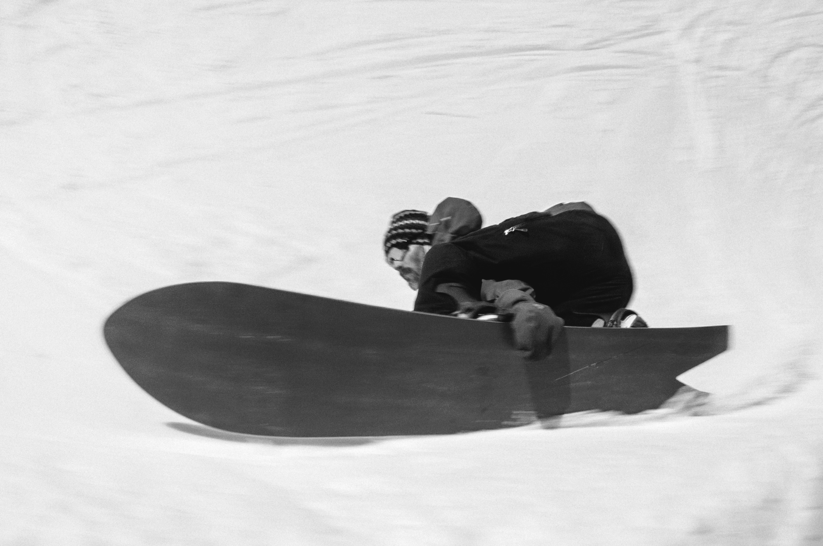Korua Dart snowboard with Nicholas performing a toeside grab on snow, showcasing the board's design and rider's skill.