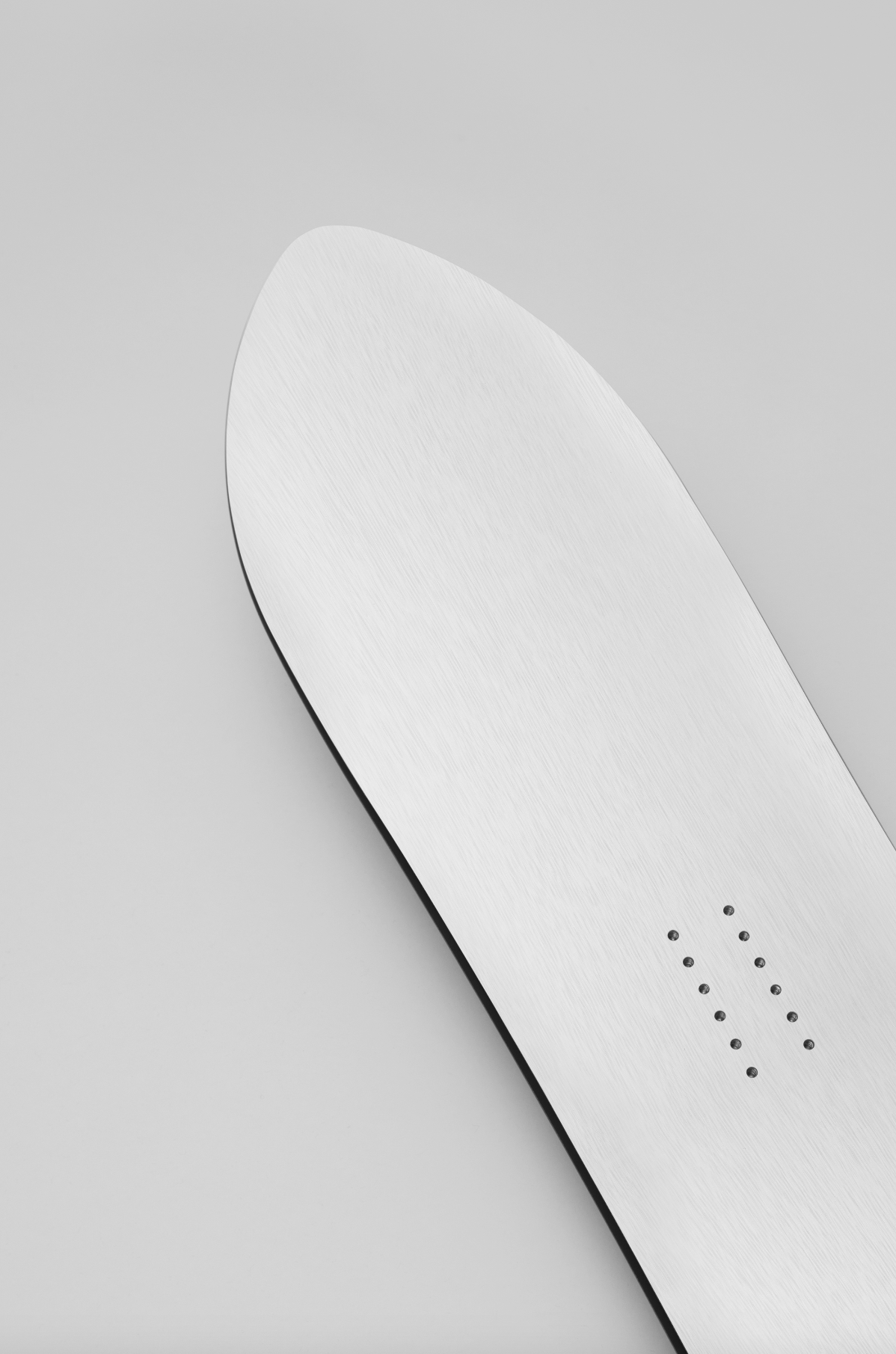 Korua Pin Tonic Snowboard with nose design, showcasing its sleek shape and graphic detail against a snowy background.