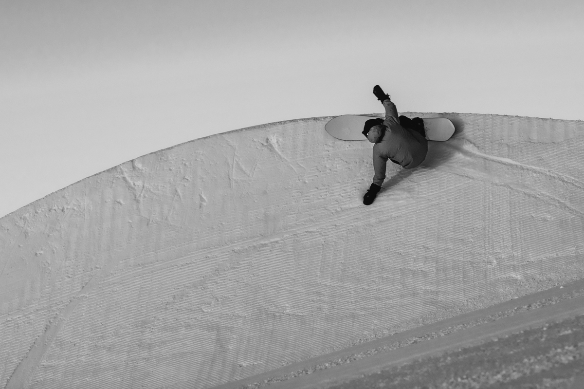Korua Pin Tonic Snowboard with pipe heelside edge, designed for snowboarding in snowy mountain terrain.