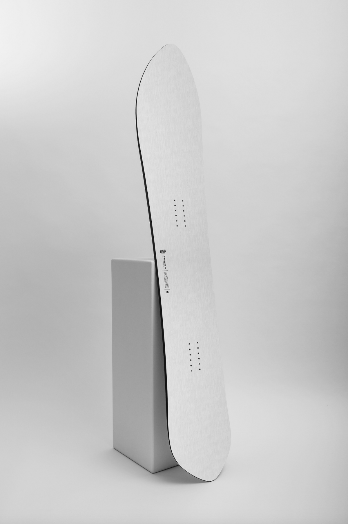 Korua Pin Tonic Snowboard on snow, showing the sleek design and branding, perfect for versatile winter snowboarding.