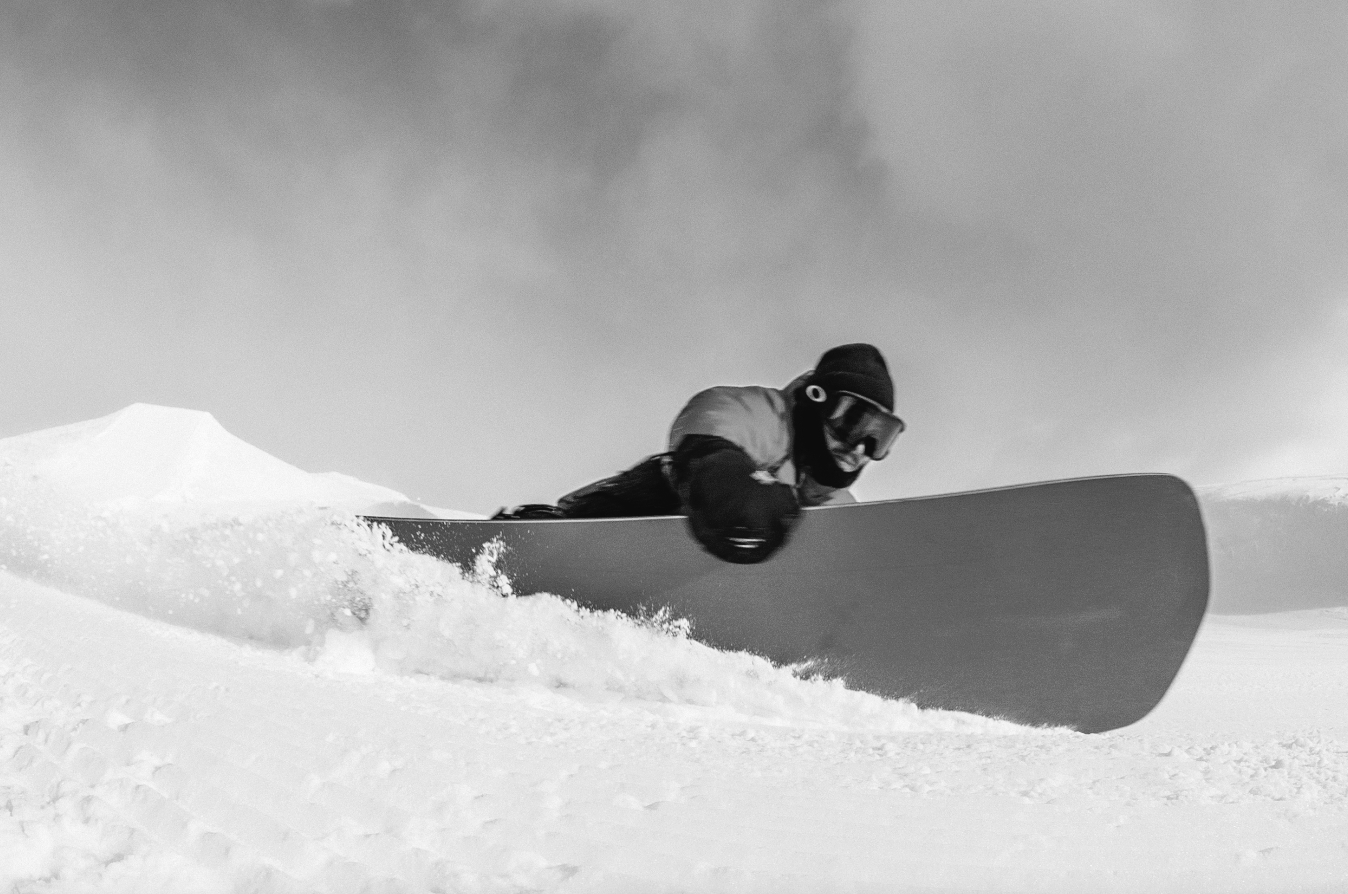 Korua Pocket Rocket snowboard showing a heelside grab trick on snow, designed for winter snowboarding enthusiasts.