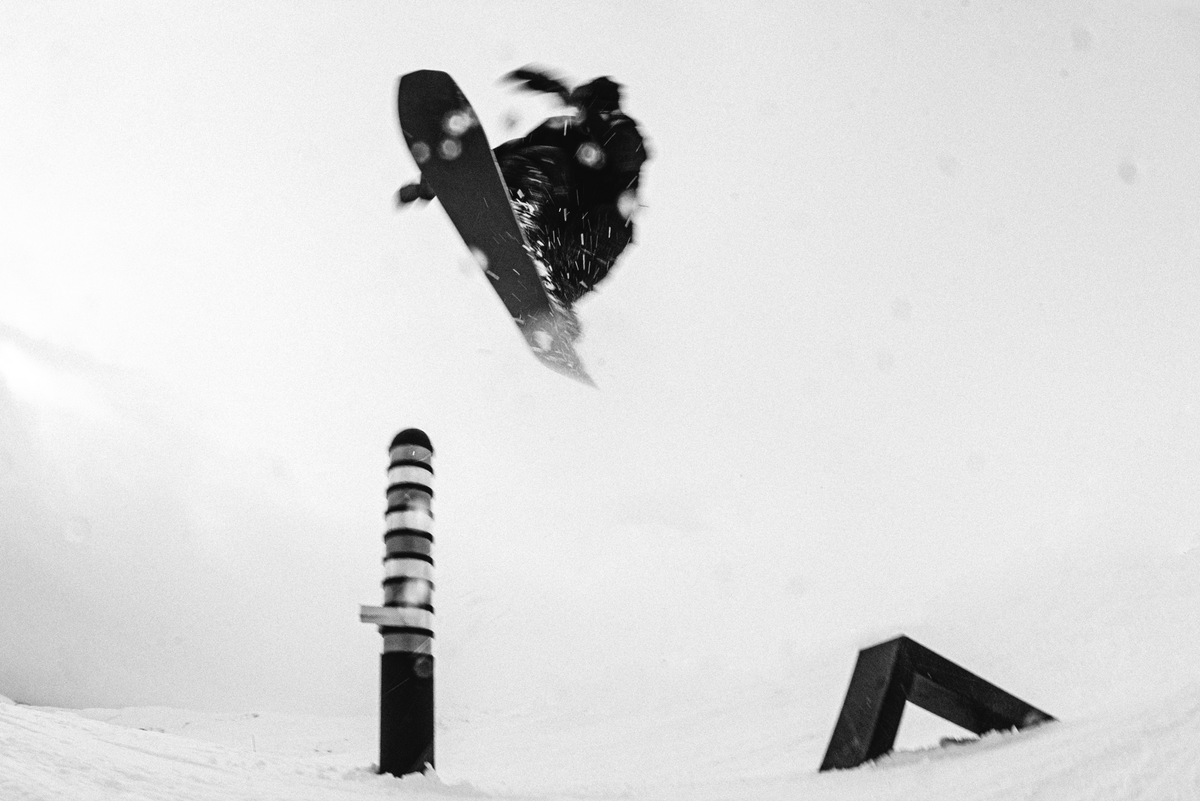 Korua Transition Finder snowboard with riding jumping over pole
