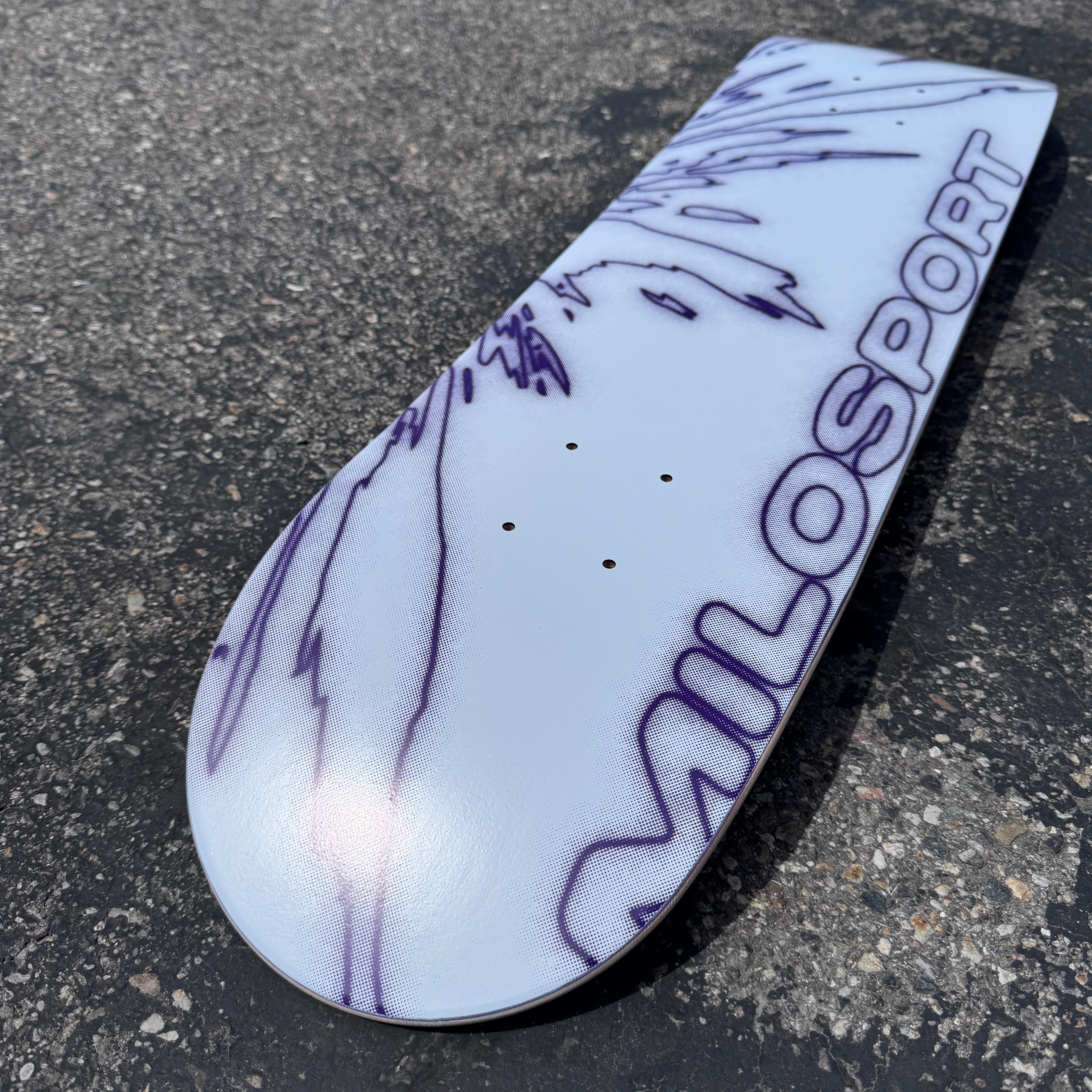 Close-up lifestyle view of the white and purple Milosport Fracture skateboard deck showing the graphic and deck shape.