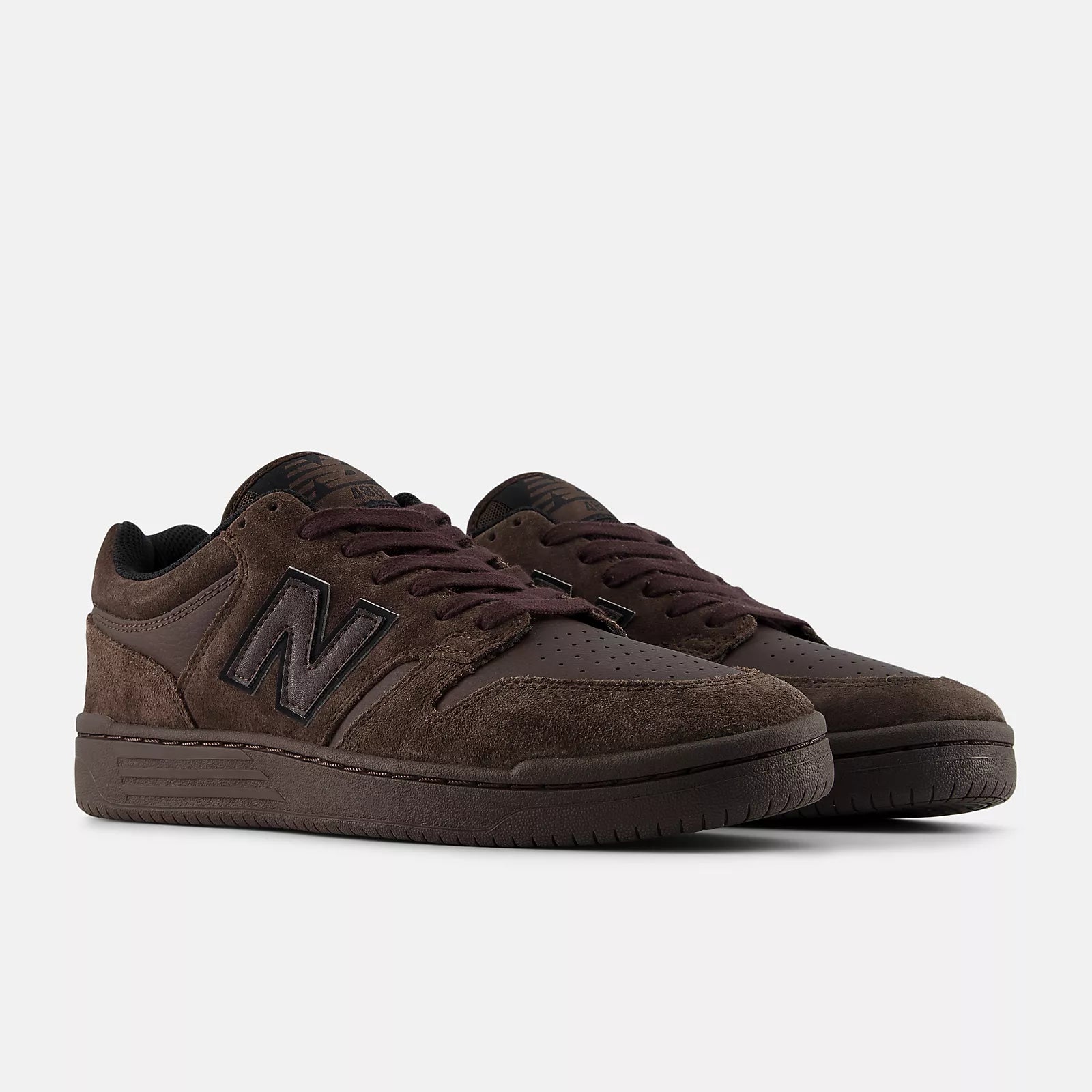 Pair of New Balance Numeric 480 skate shoes in Chocolate Brown shown from a front three-quarter angle with tonal brown uppers and cupsoles.