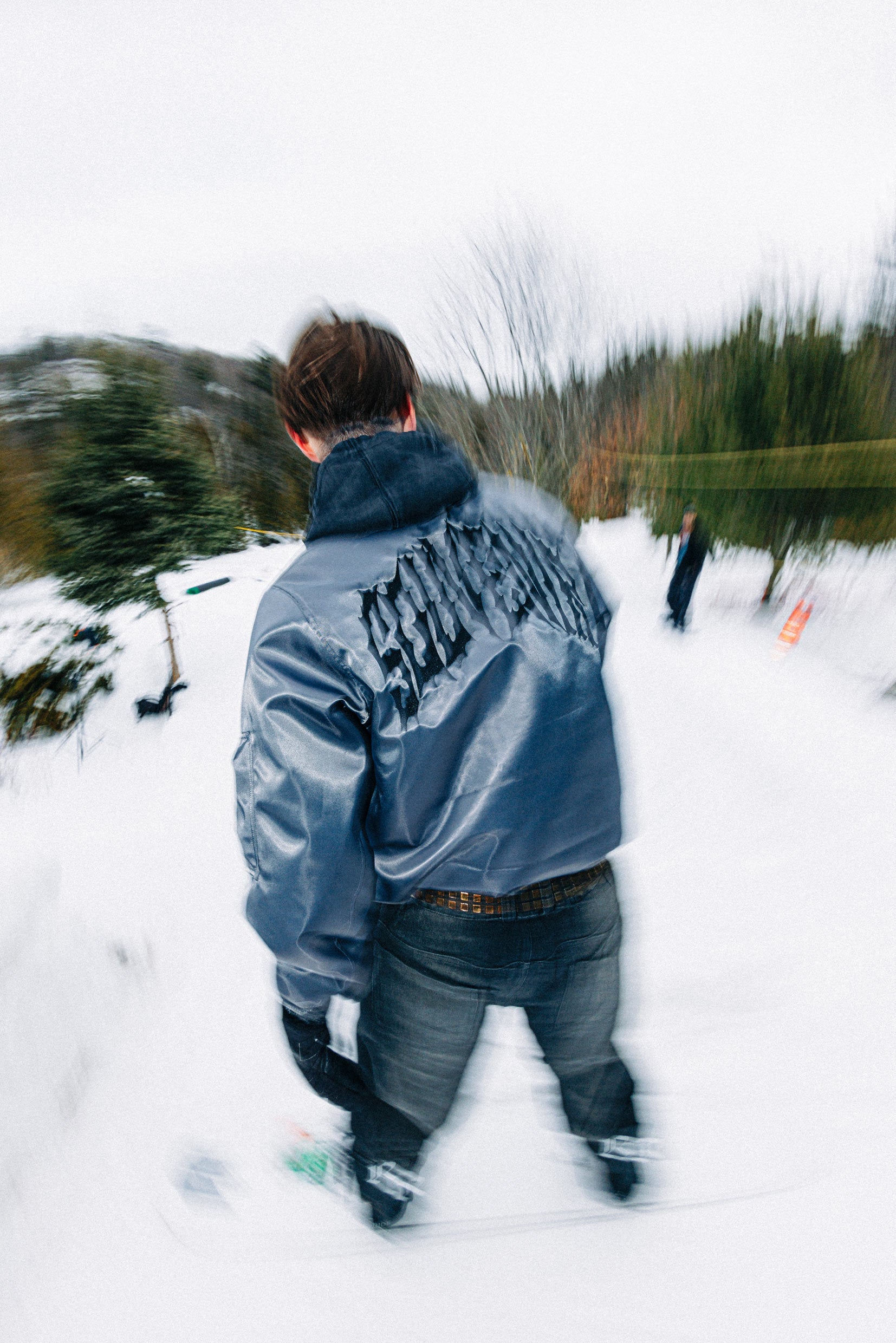 Rear lifestyle view of the Souvenir 3 Ply Denim Pant 2027 in Black Denim worn in the snow with a grey Souvenir jacket.
