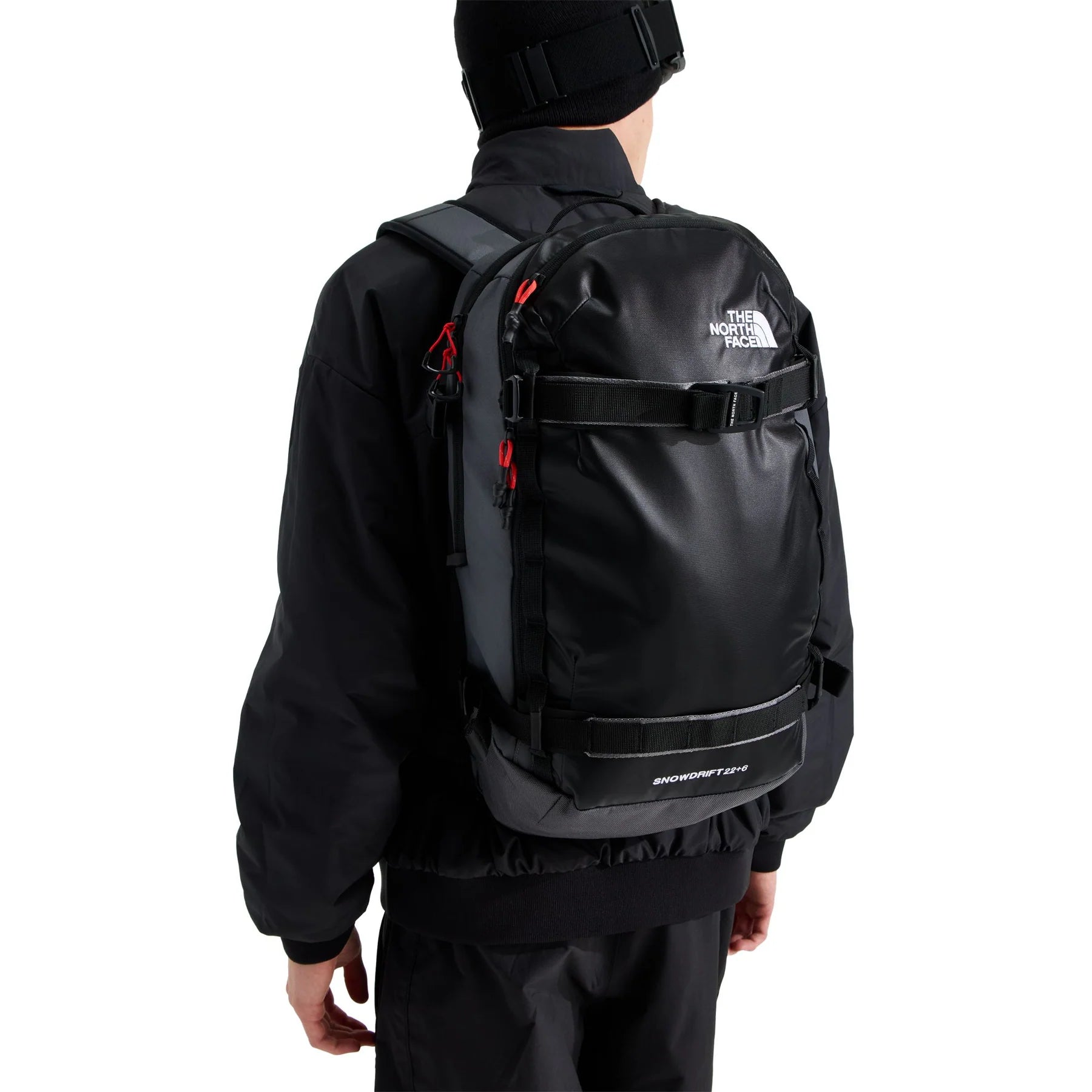 The North Face Snowdrift 22 + 6 snow backpack worn on a model, showing its close-to-body profile, carry straps and compact fit.