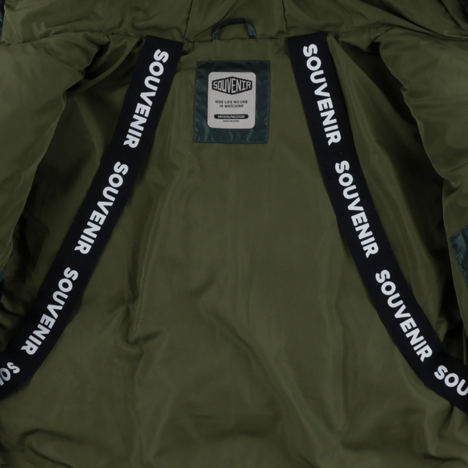 Souvenir Mountain Puffy 2026 jacket with deep forest green color, interior strap details, and puffy insulated design.