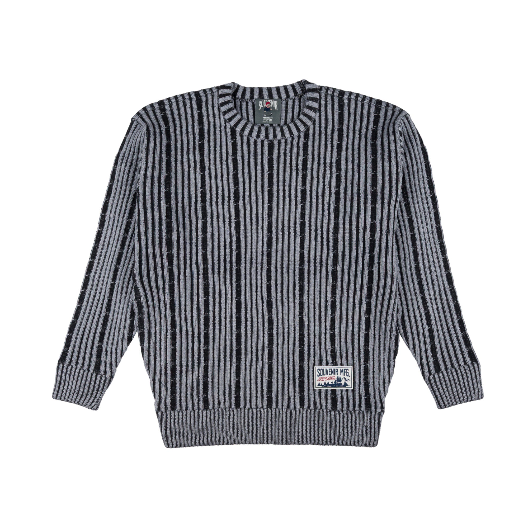 A long-sleeve crewneck souvenir sweater with vertical black and gray stripes, featuring a ribbed collar, cuffs, and hem, with a small brand patch on the lower right front.