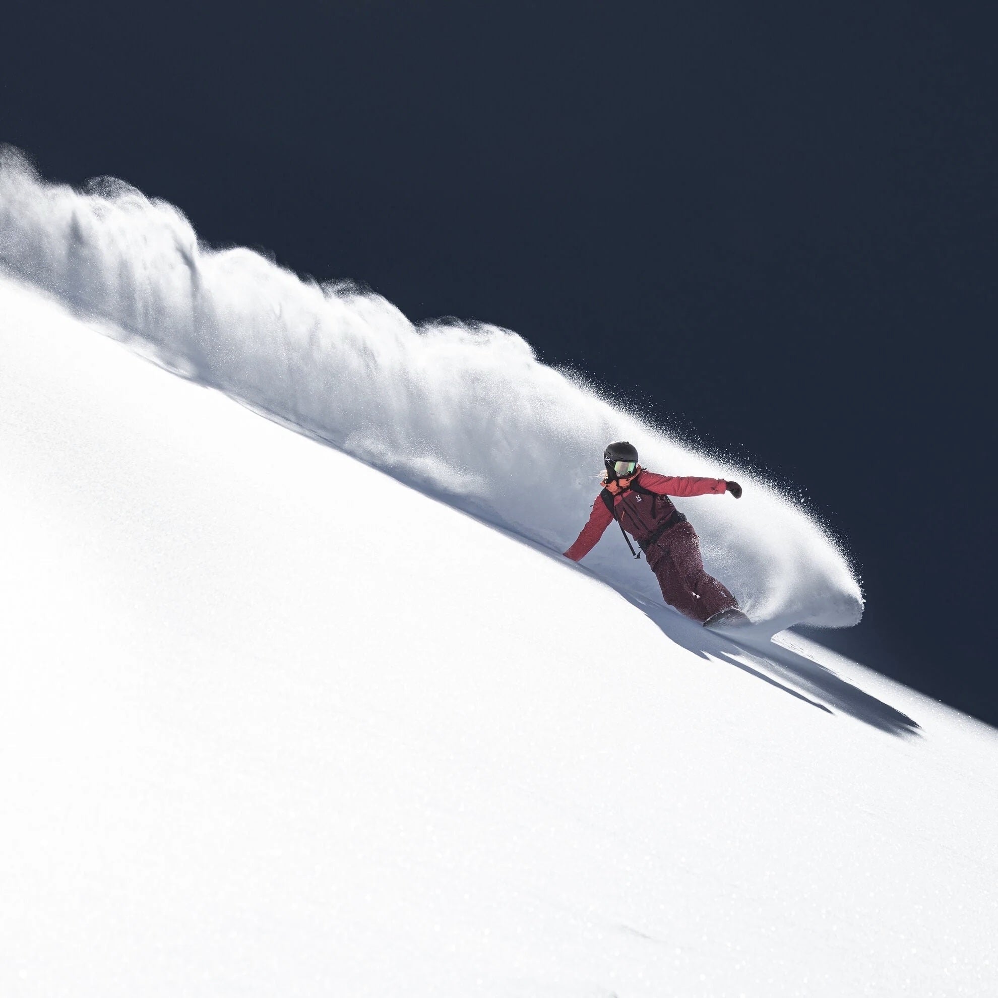 nidecker altai snowboarder with a red jacket doing an epic powder slash toeside
