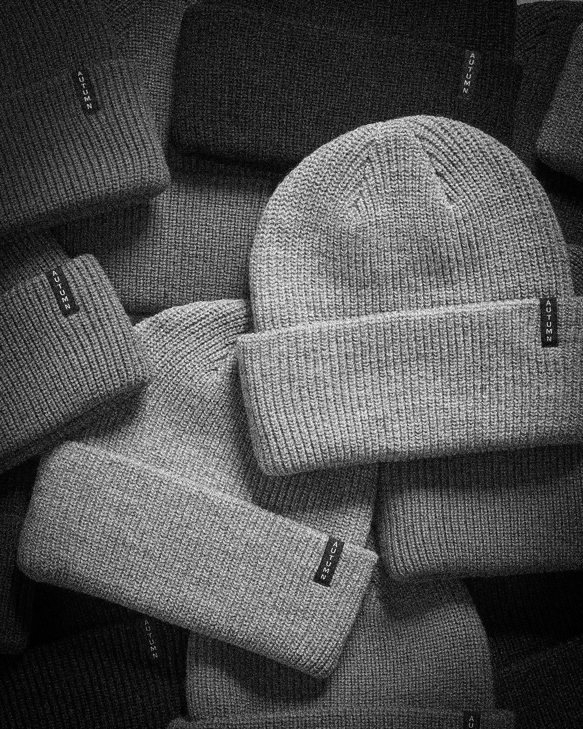 Black and white product image of assorted Autumn knit beanies stacked together, used for the Milosport Beanies collection.