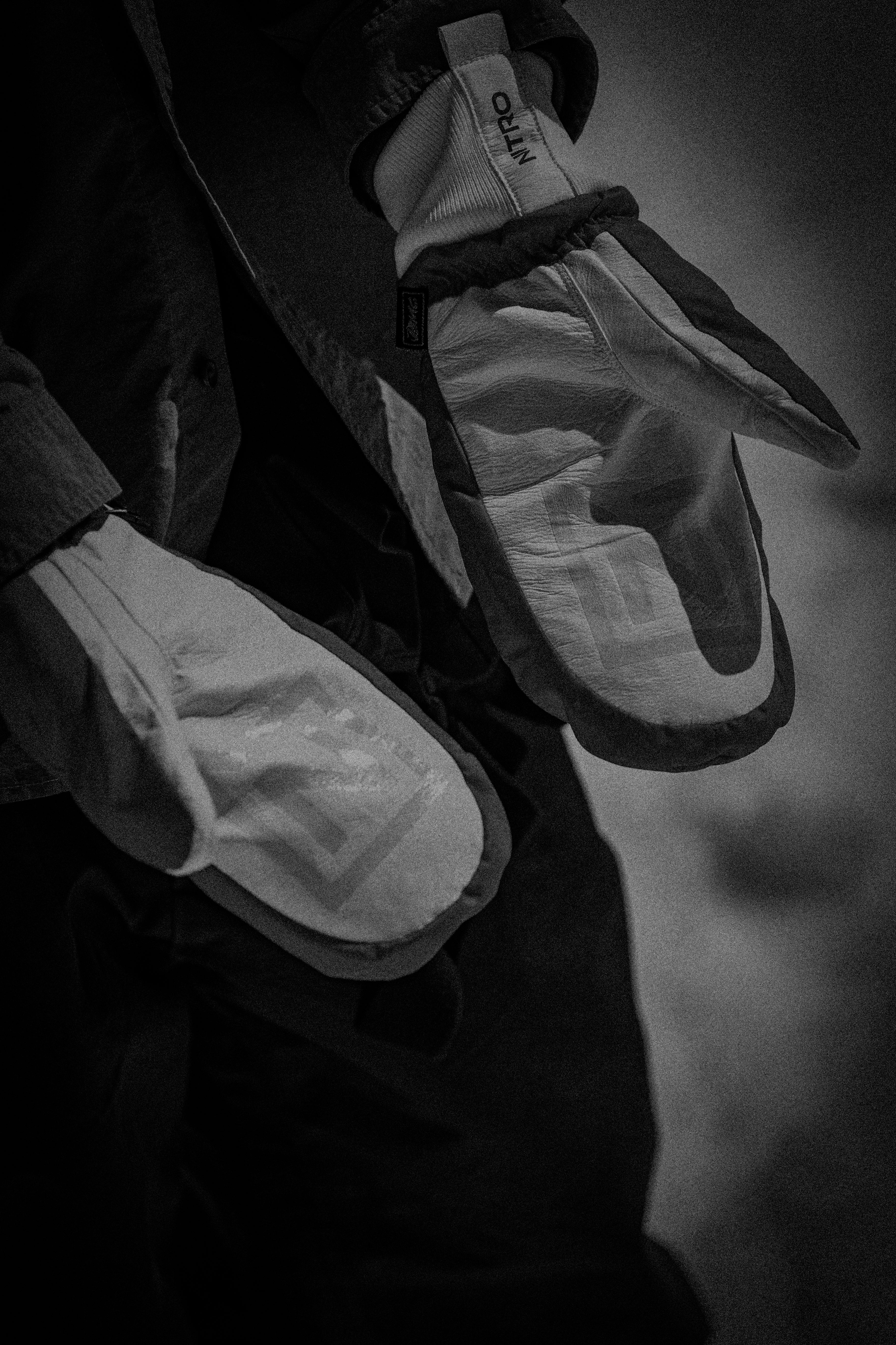 Black and white close-up of a snowboarder wearing insulated mittens, used for the Milosport Mittens & Gloves collection.