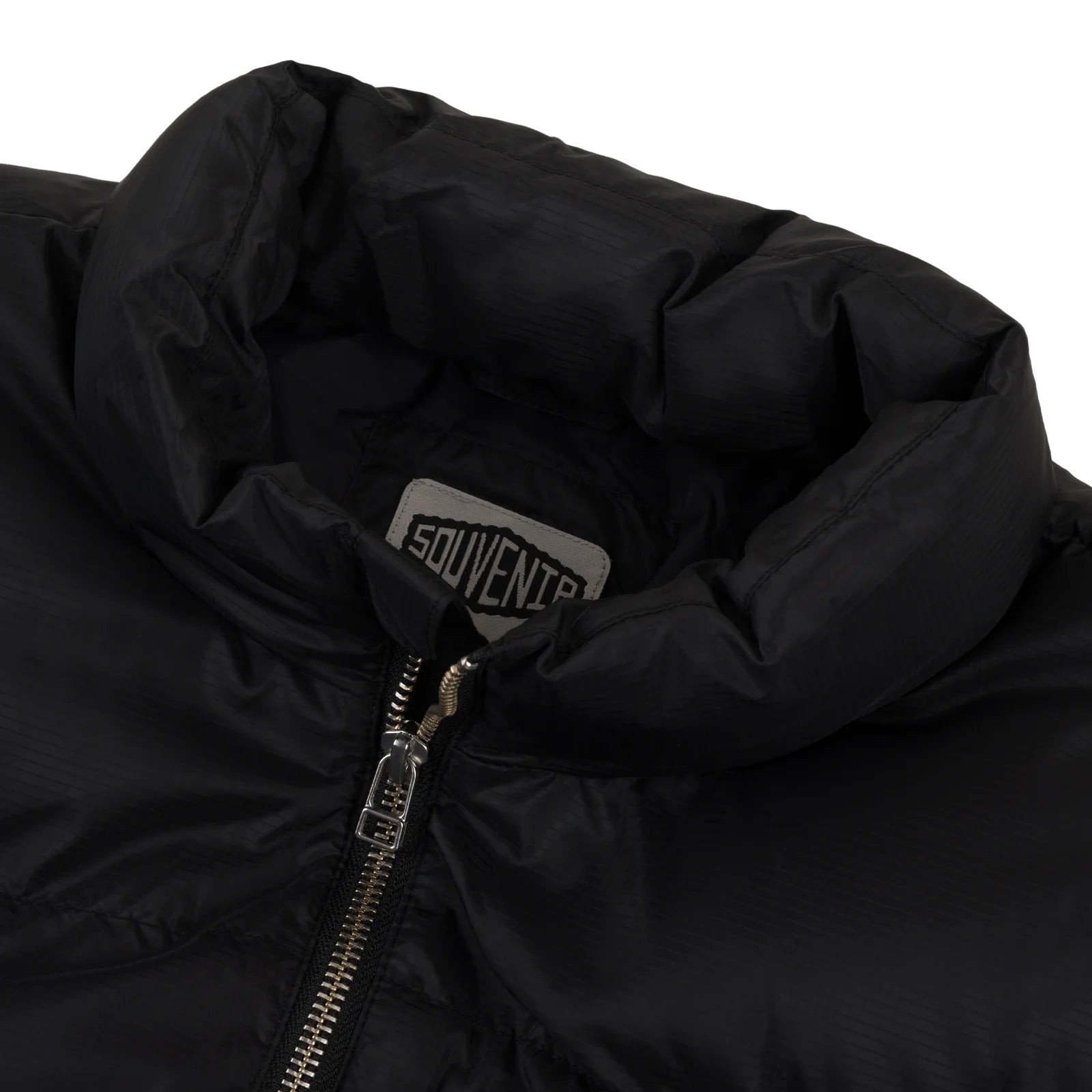 Close-up of black Souvenir Everyday Puffer 2026 jacket showing quilted design and shiny fabric.