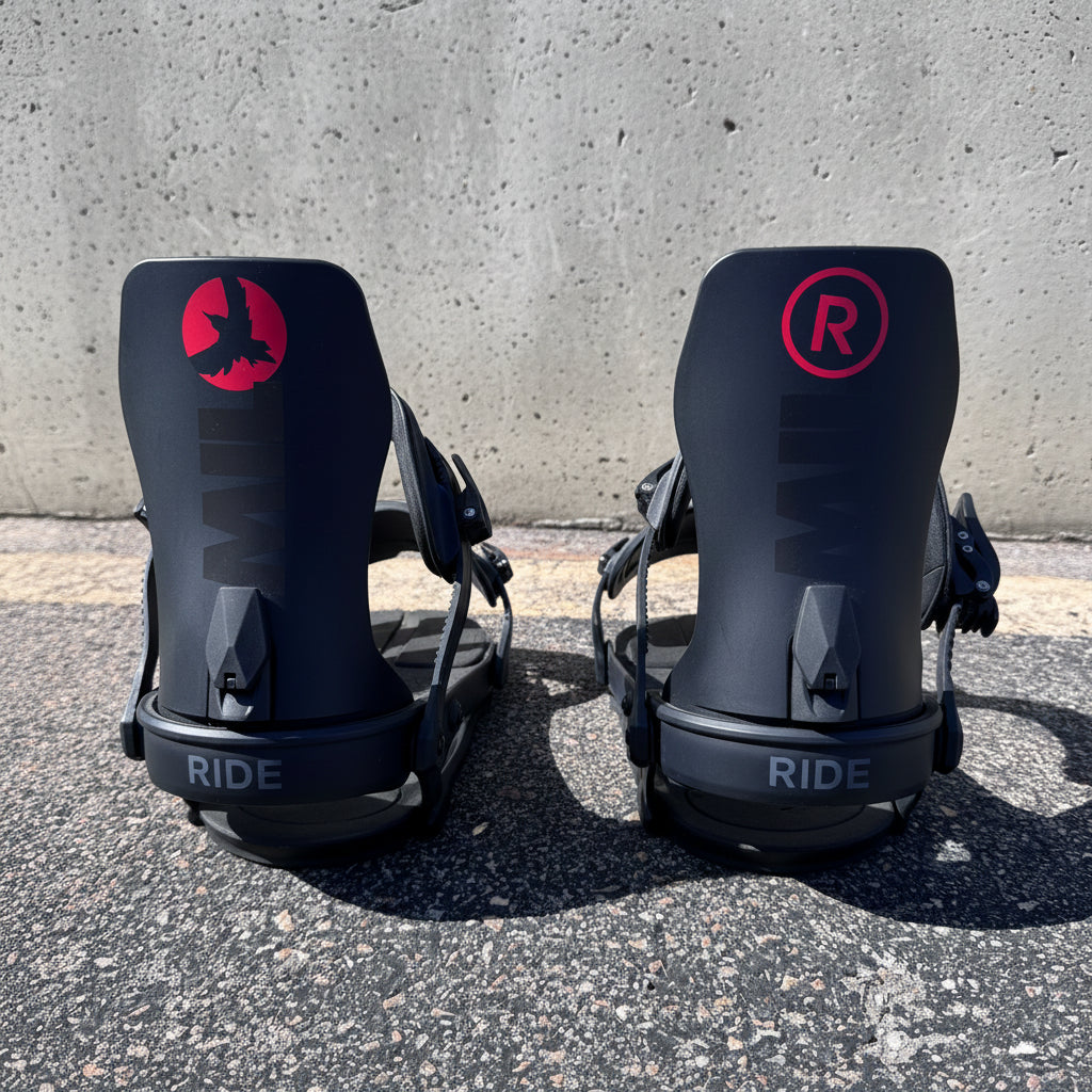 Two black snowboard bindings with 'RIDE' branding on a concrete surface with graffiti in the background.