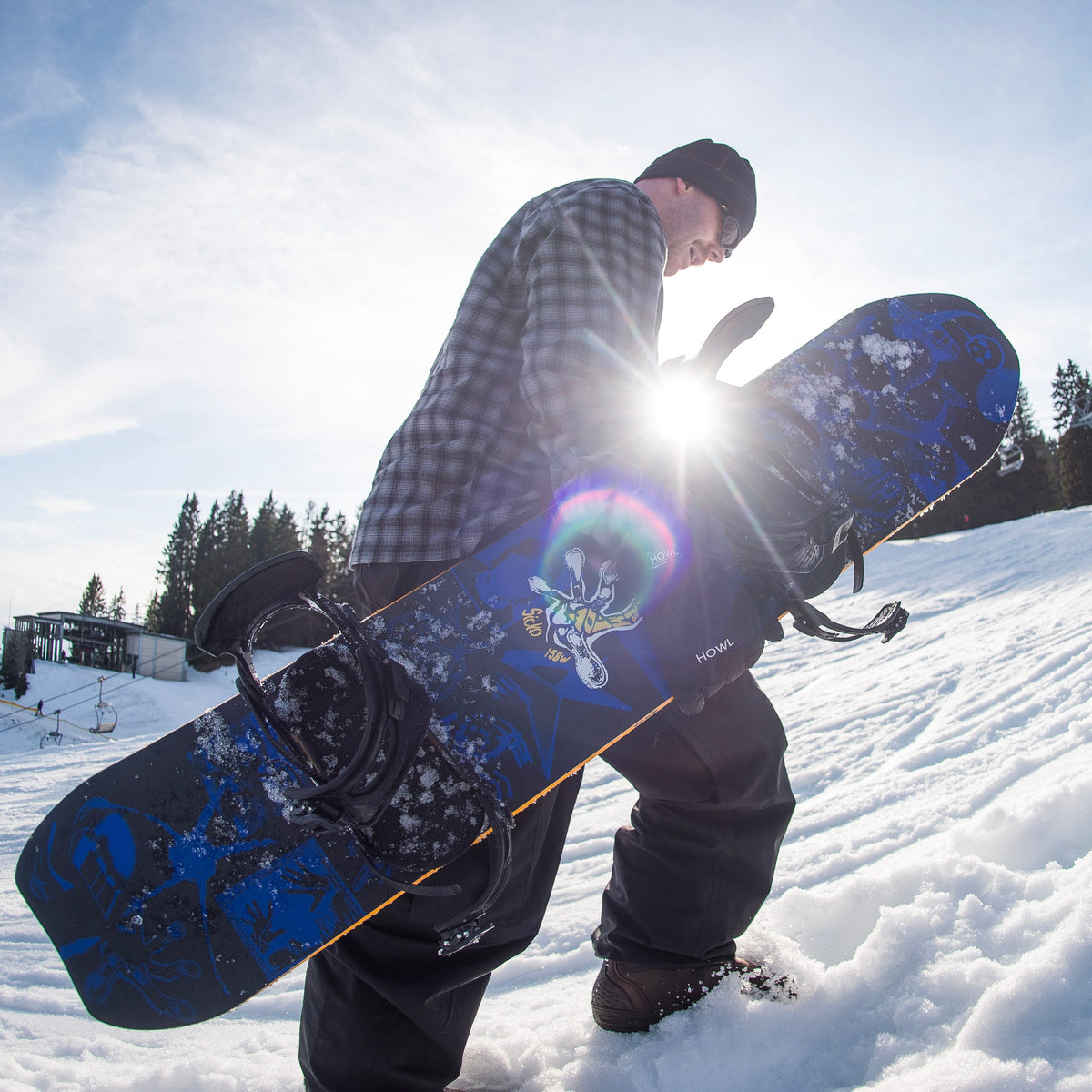 Armada Sicko snowboard in winter snow, featuring a rider hiking in snowy mountain terrain, showcasing the snowboard's design and durability.
