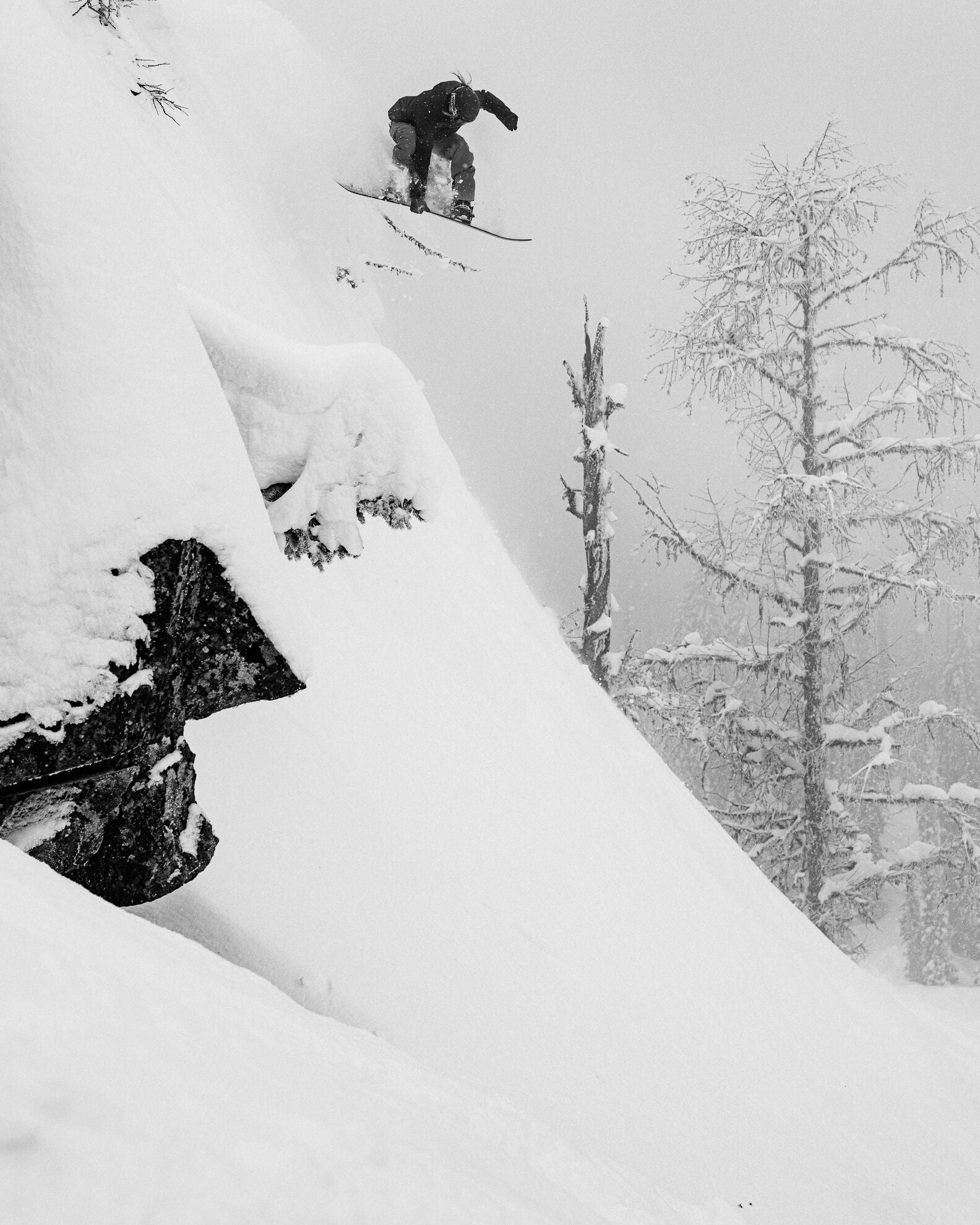 Jones Men's Mountain Twin Pro Snowboard with cliff drop feature, designed for versatile mountain snowboarding in snow conditions.