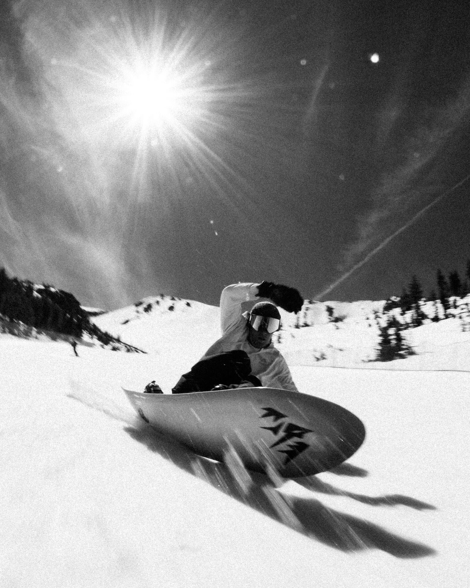 Jones Storm Wolf Snowboard 2027 resting on groomed snow, showcasing its graphic design and versatile shape for snowboarding.