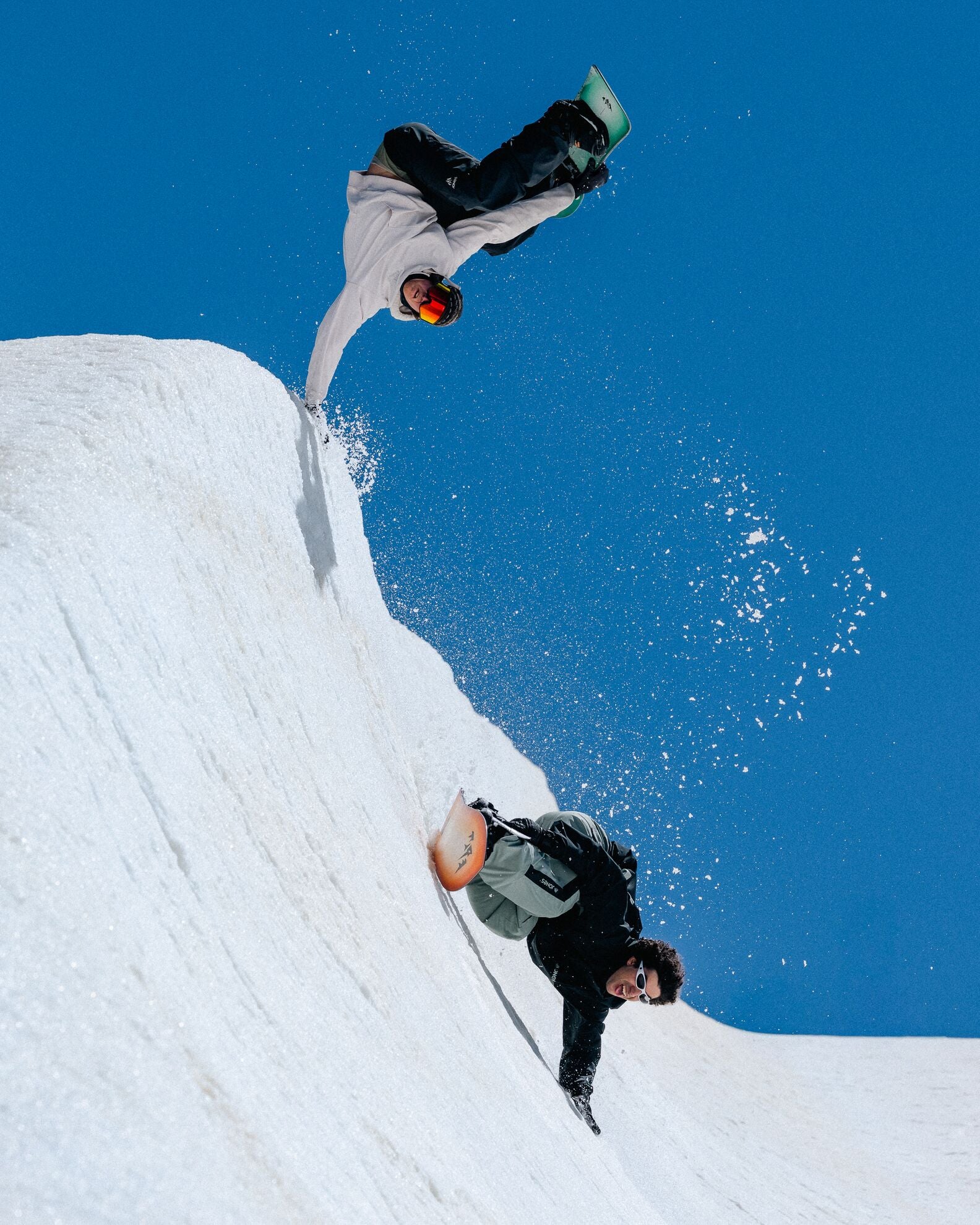 Jones Twincraft Snowboard 2027, snowboarding scene with two riders on Jones snowboard in a snowy mountain landscape.