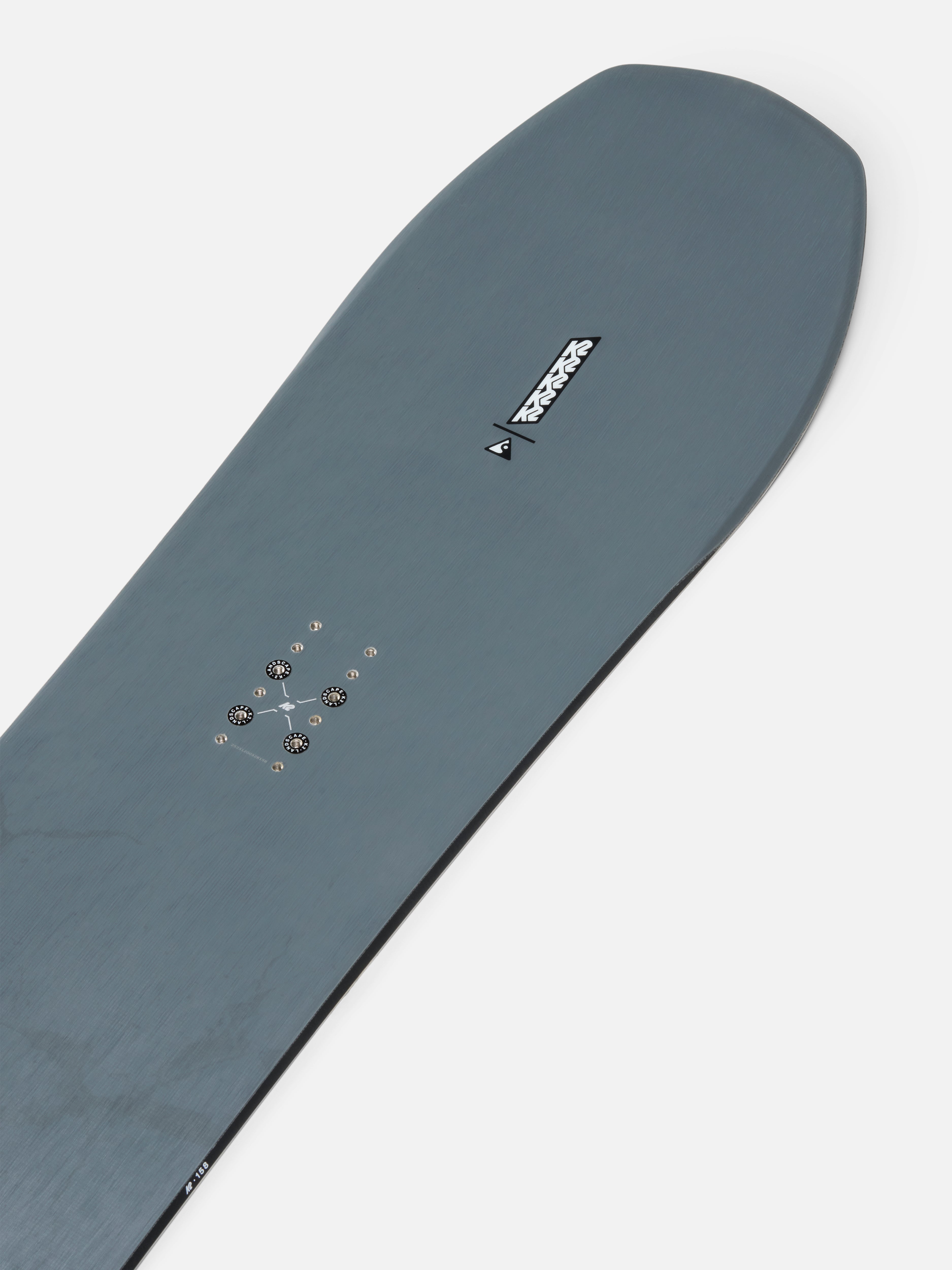 K2 Excavator Snowboard 2027 nose view showing its design and graphics on a snowy landscape.