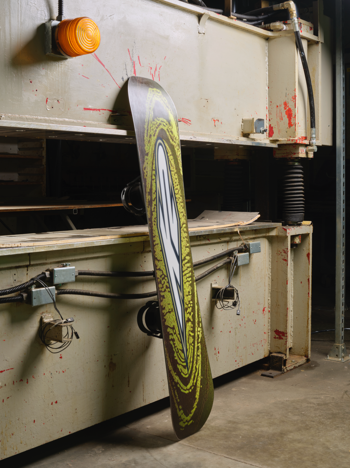 K2 Hypnotist snowboard 2027 with snow-covered base and workshop setting, showcasing the versatile design for all-mountain riding.