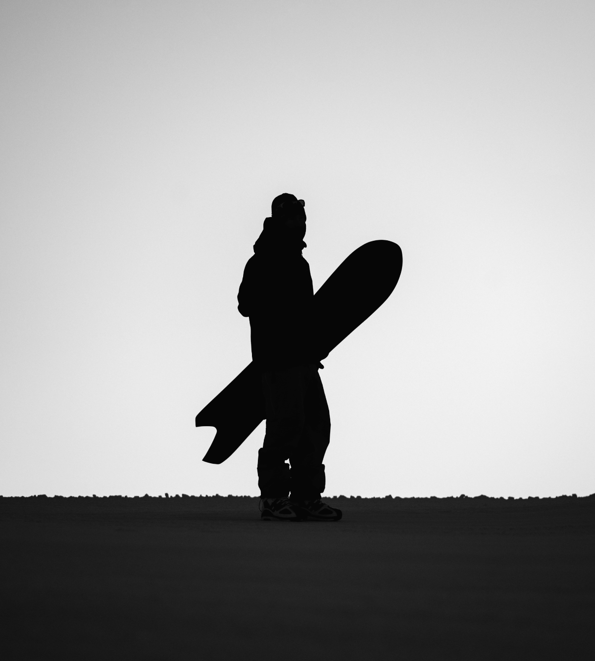 Silhouette of Korua Apollo Snowboard designed for snowboarding, showcasing its shape and curves on a snowy background.