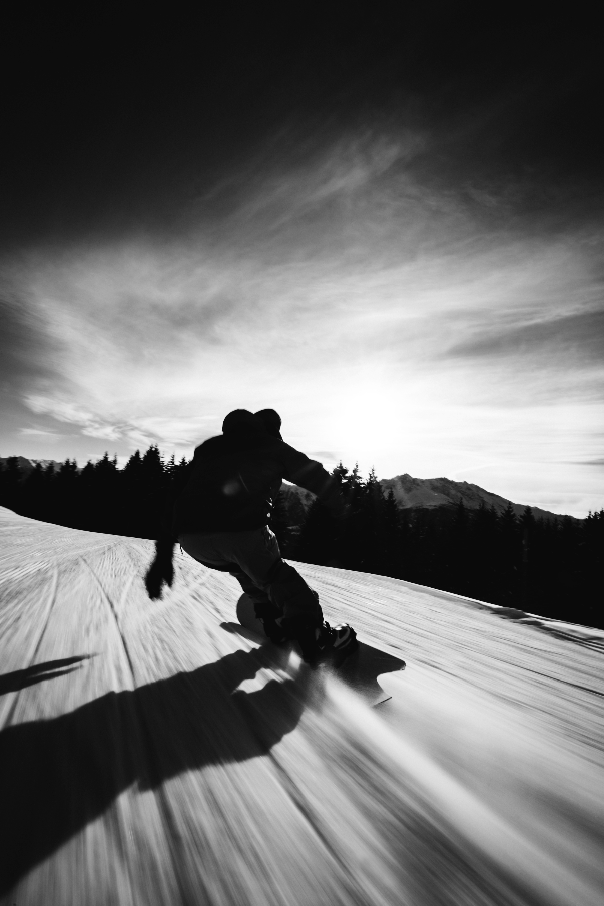 Korua Apollo Snowboard in black and white, shown on snow slope with a rider in winter gear.