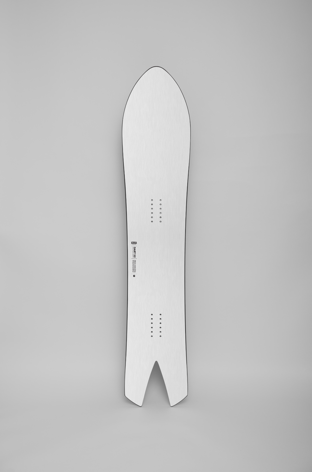 Korua Dart snowboard with a colorful topsheet design, standing upright on a snow-covered surface, showcasing its shape and graphics.