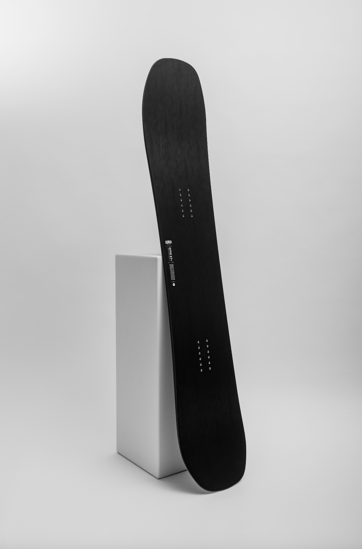 Korua Otto Plus Snowboard in a snow-covered outdoor setting, showcasing its design and shape for winter snowboarding.