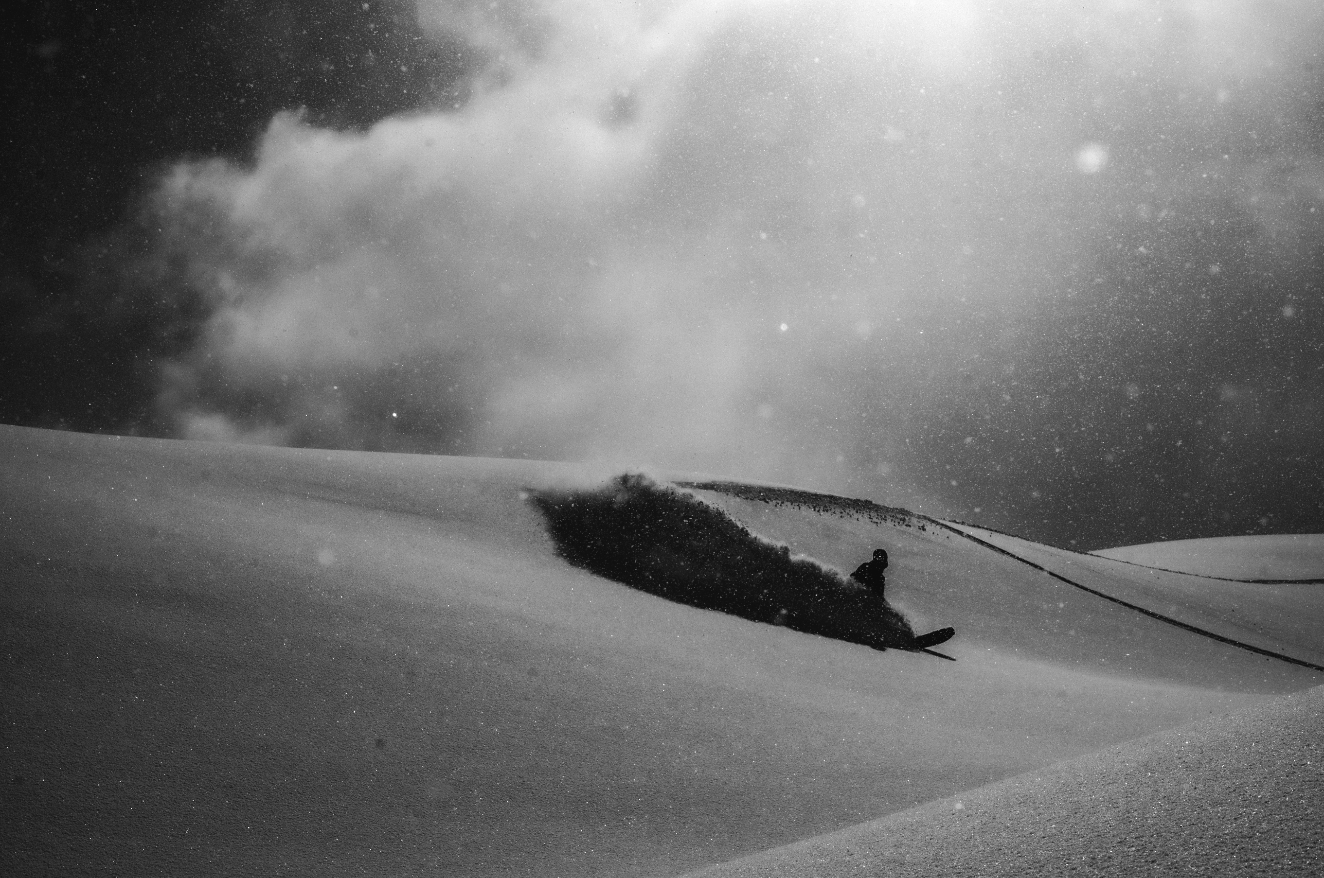 Korua Transition Finder snowboard with a sleek design, shown on snow with a powder heelside turn