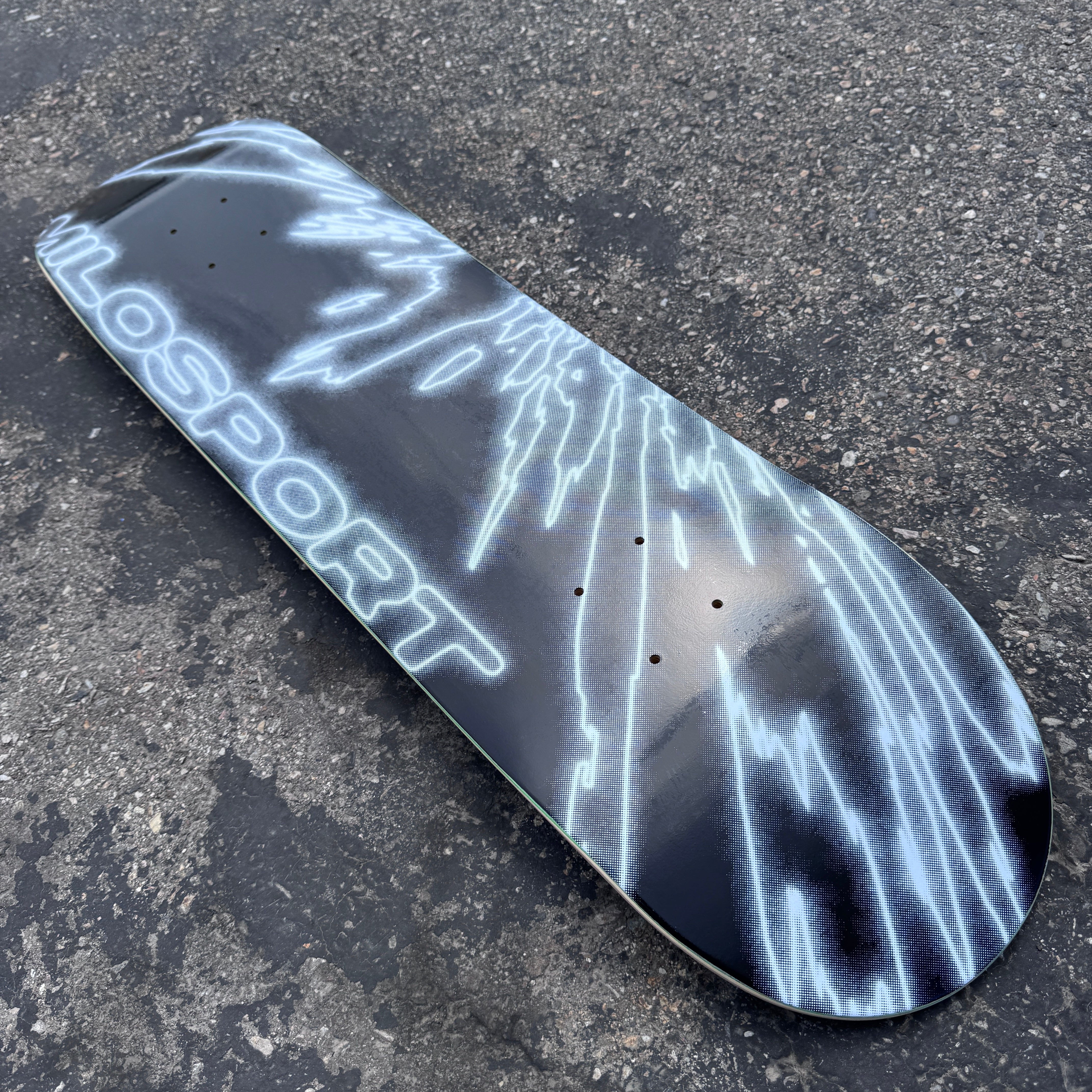 Close-up of the white fractured line artwork and Milosport logo on the black  Fracture skateboard deck.