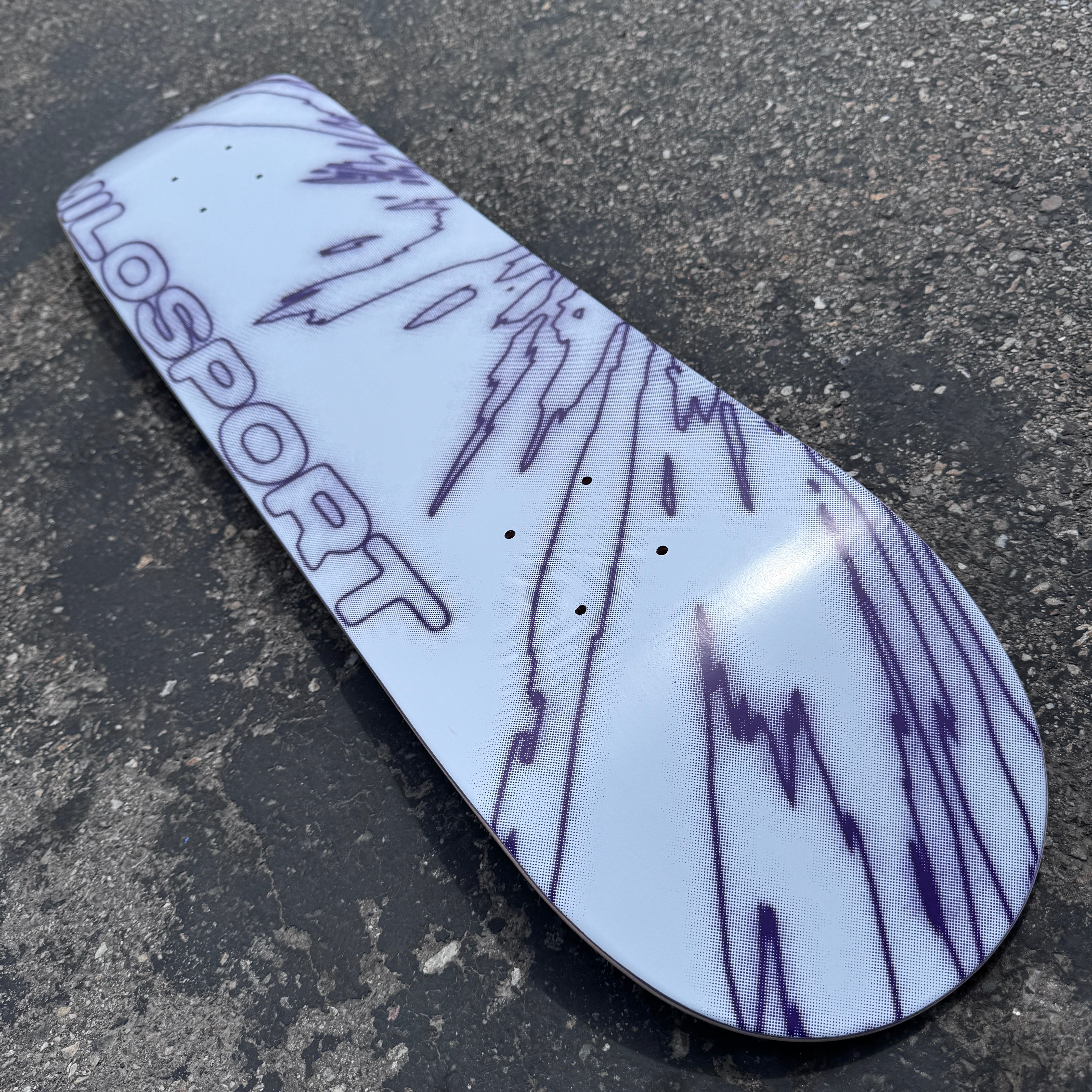 Close-up of the fractured line artwork and Milosport branding on the white and purple Elbow Fracture skateboard deck.