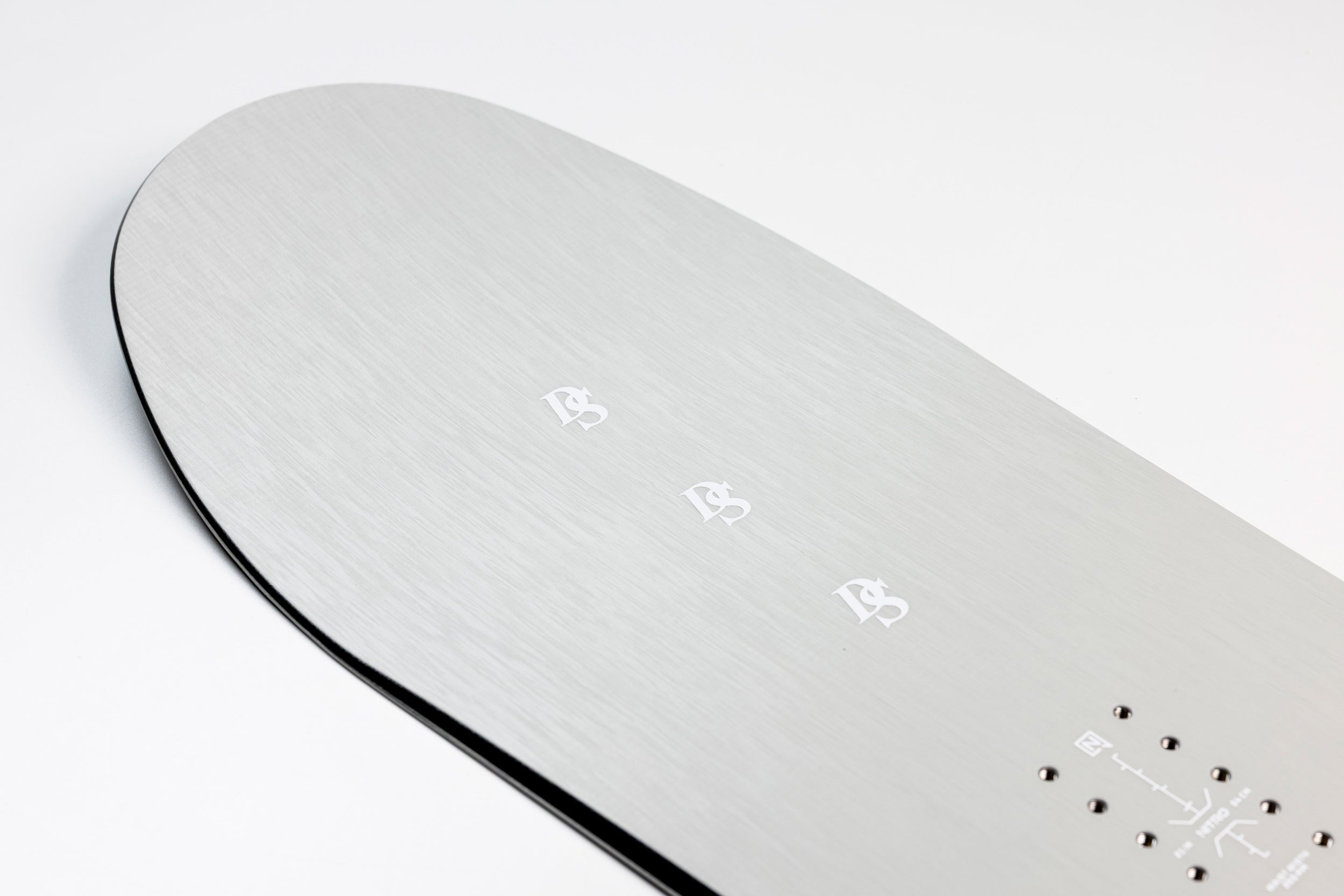 Close-up of the nose of the Nitro Santoku Snowboard 2027, showing binding inserts and detailed snowboard surface.