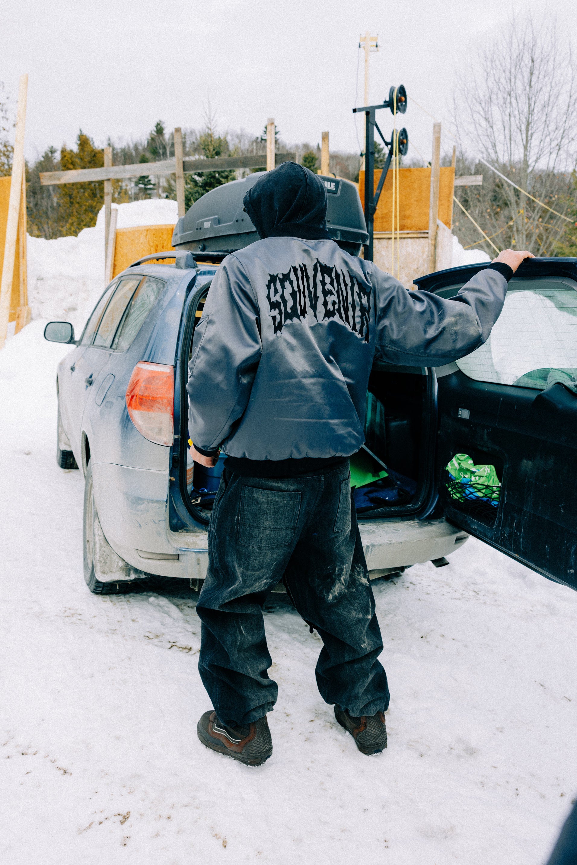Full rear view of the Souvenir 3 Ply Denim Pant 2027 in Black Denim showing the loose workwear fit and faded denim finish in the snow.