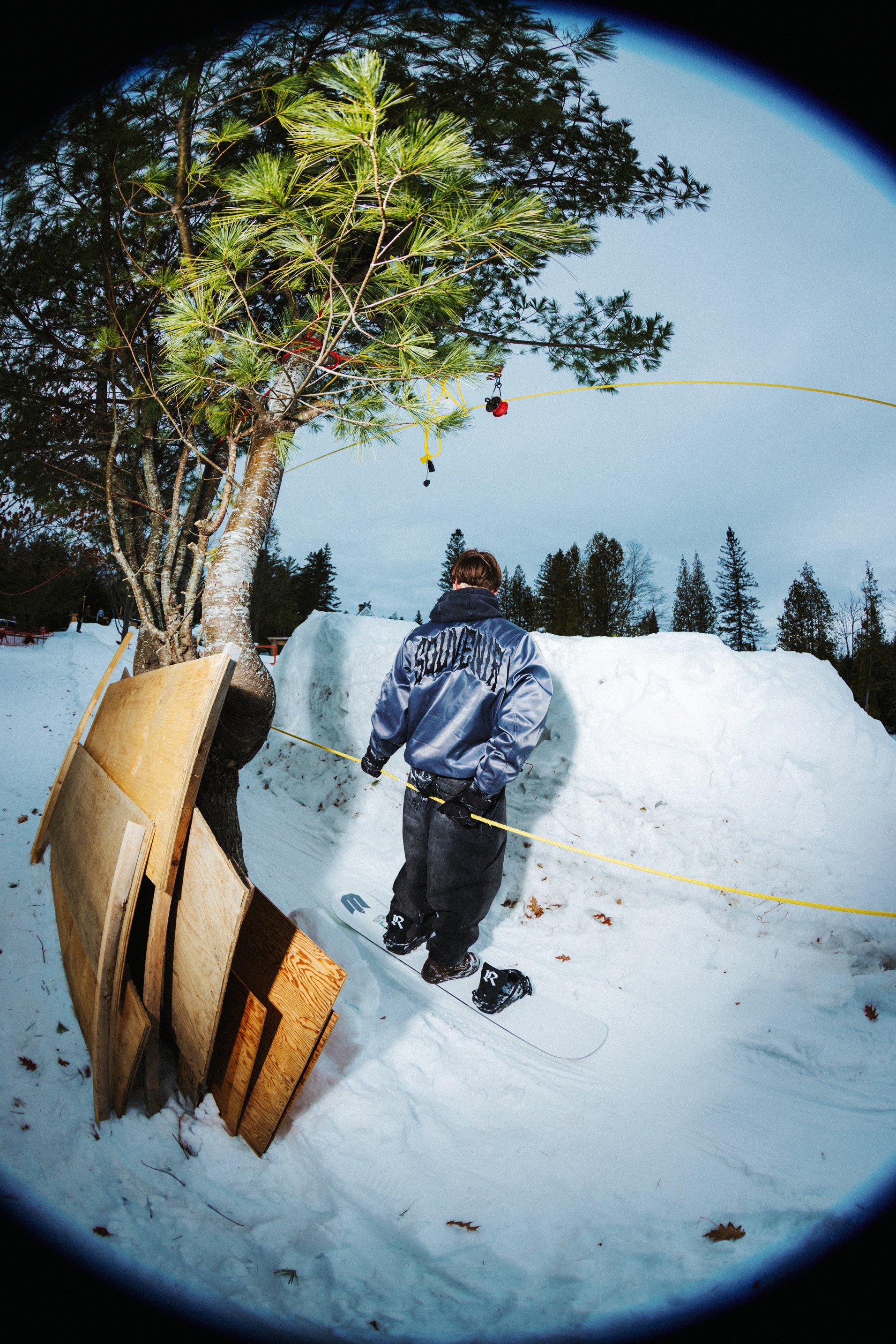 Snowboarder wearing the Souvenir 3 Ply Denim Pant 2027 in Black Denim while standing on a snowboard in a snowy outdoor setting.