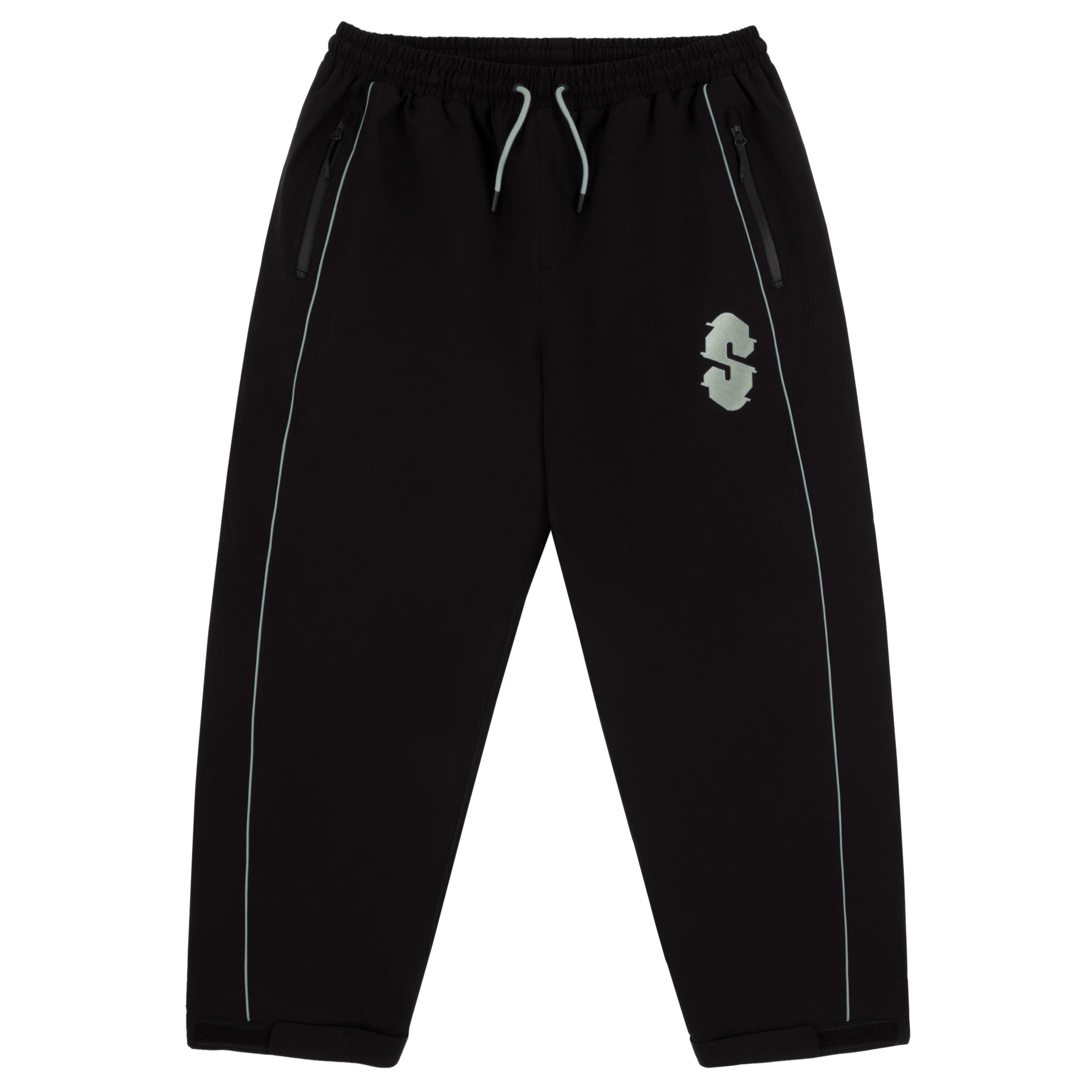 Souvenir Insulated Track Pant 2027 in Black shown from the front with baggy track fit, elastic drawstring waist, zippered hand pockets, reflective piping and embroidered Souvenir thigh logo.