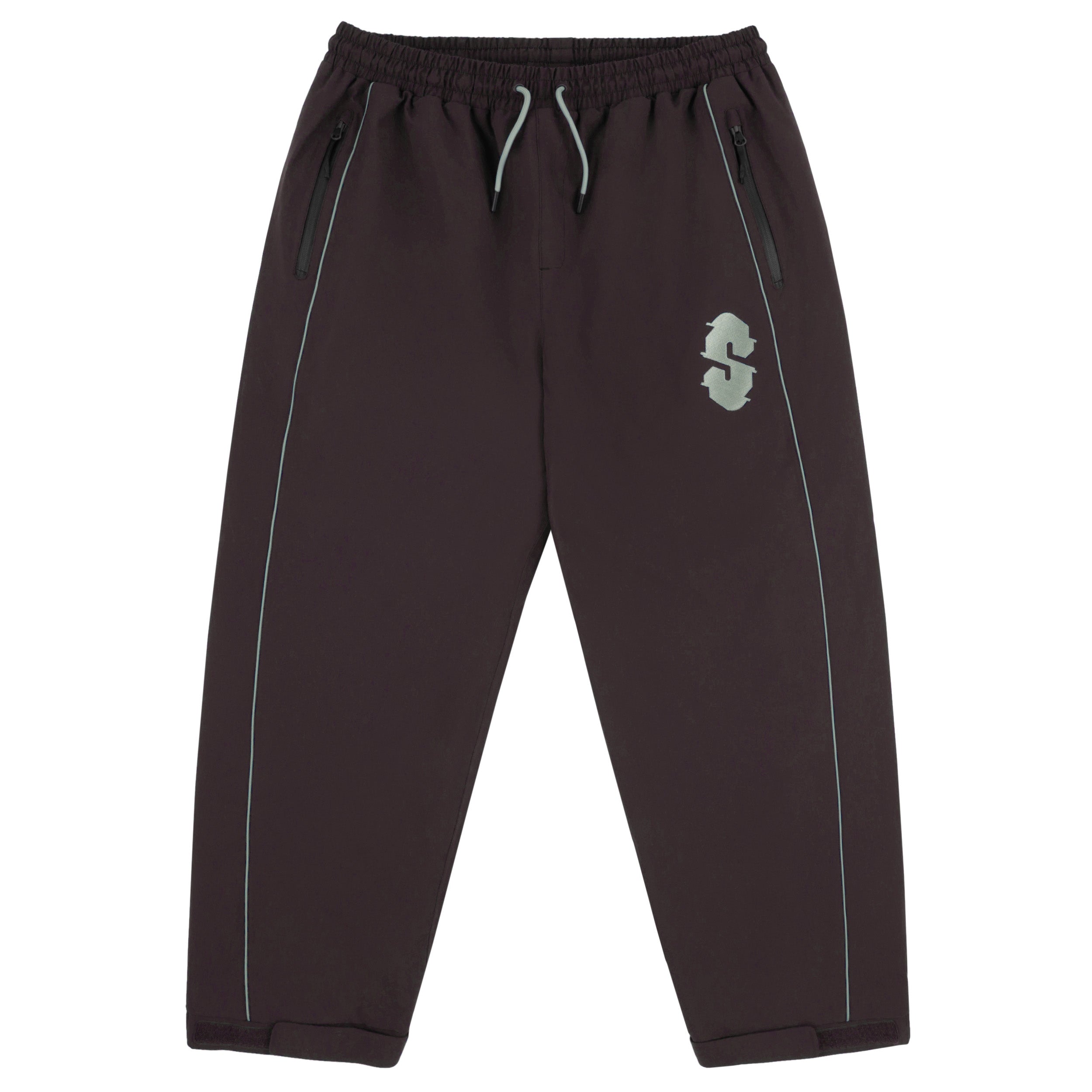 Souvenir Insulated Track Pant 2027 in Cocoa shown from the front with baggy track fit, elastic drawstring waist, zippered hand pockets, reflective piping and embroidered Souvenir thigh logo.