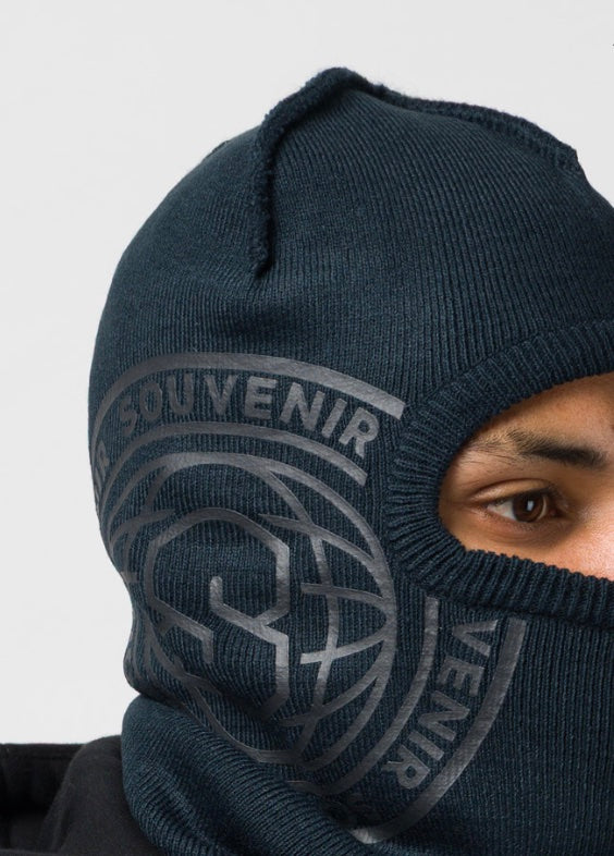 On-body view of the Souvenir Printed Burglar Mask in Black showing the full-face rib knit fit and oversized tonal Souvenir globe graphic.