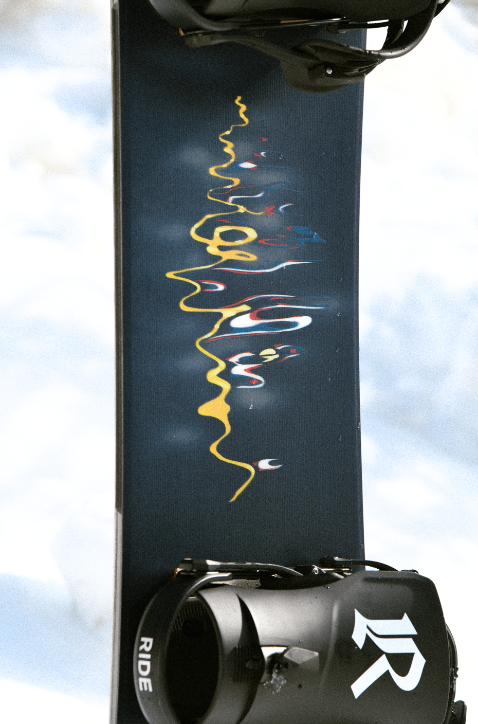 Ride Current Snowboard 2027 with colorful top sheet and bindings, ready for winter snowboarding adventures.